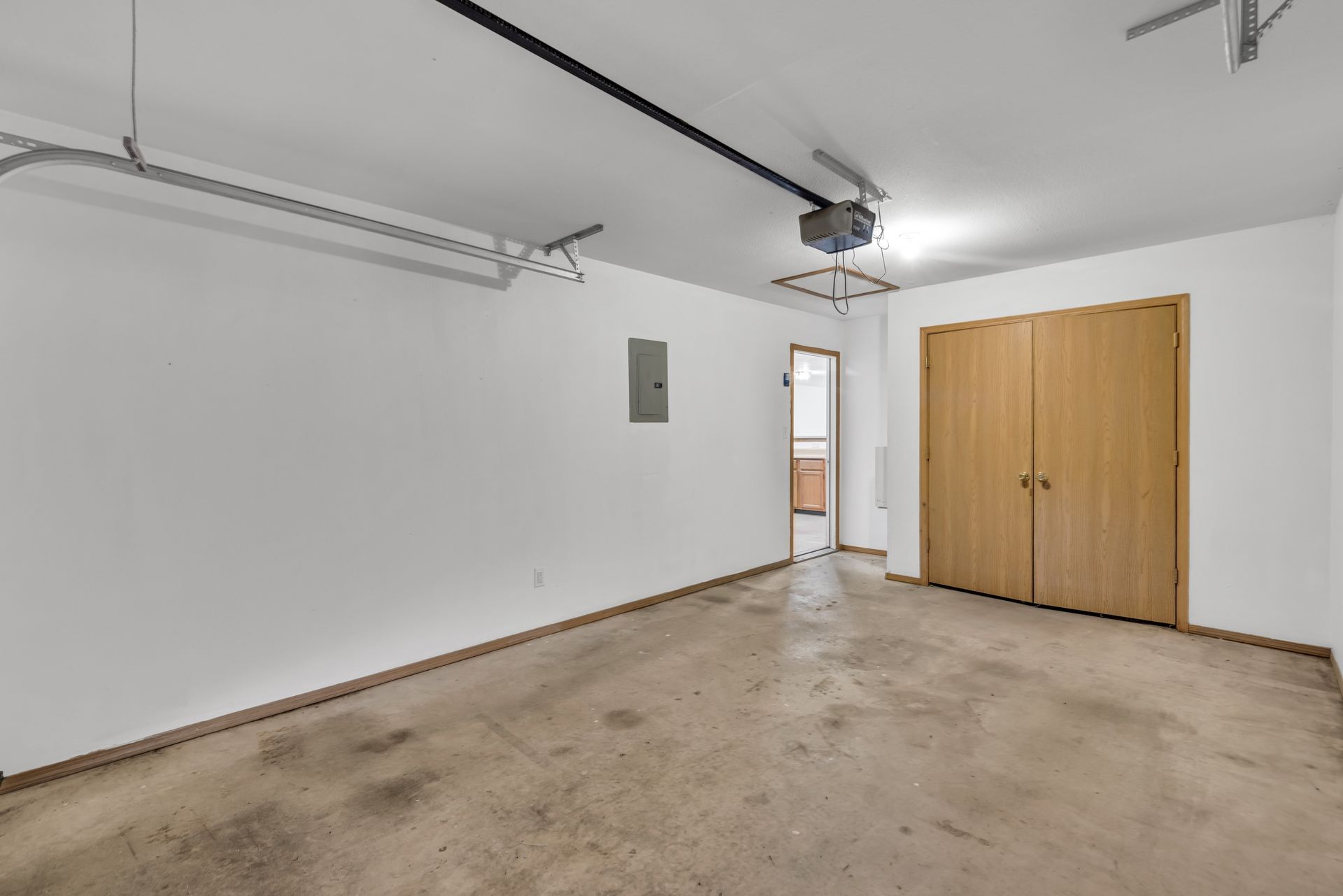 An empty garage with a garage door open and a ceiling fan.