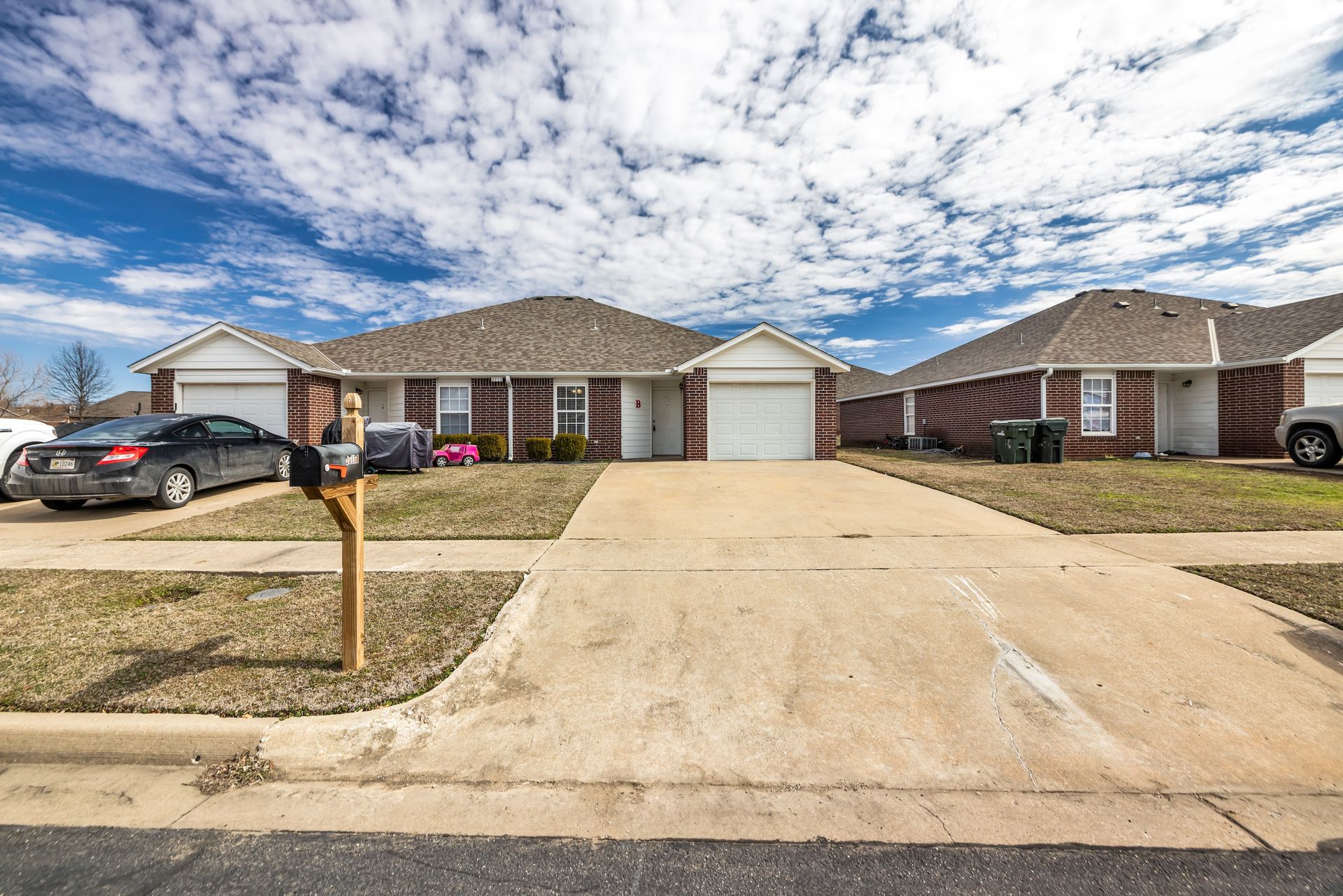 A couple of cars are parked in front of a row of houses.