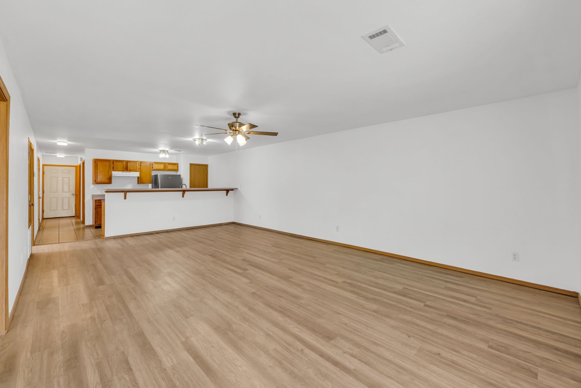 An empty living room with hardwood floors and a ceiling fan.