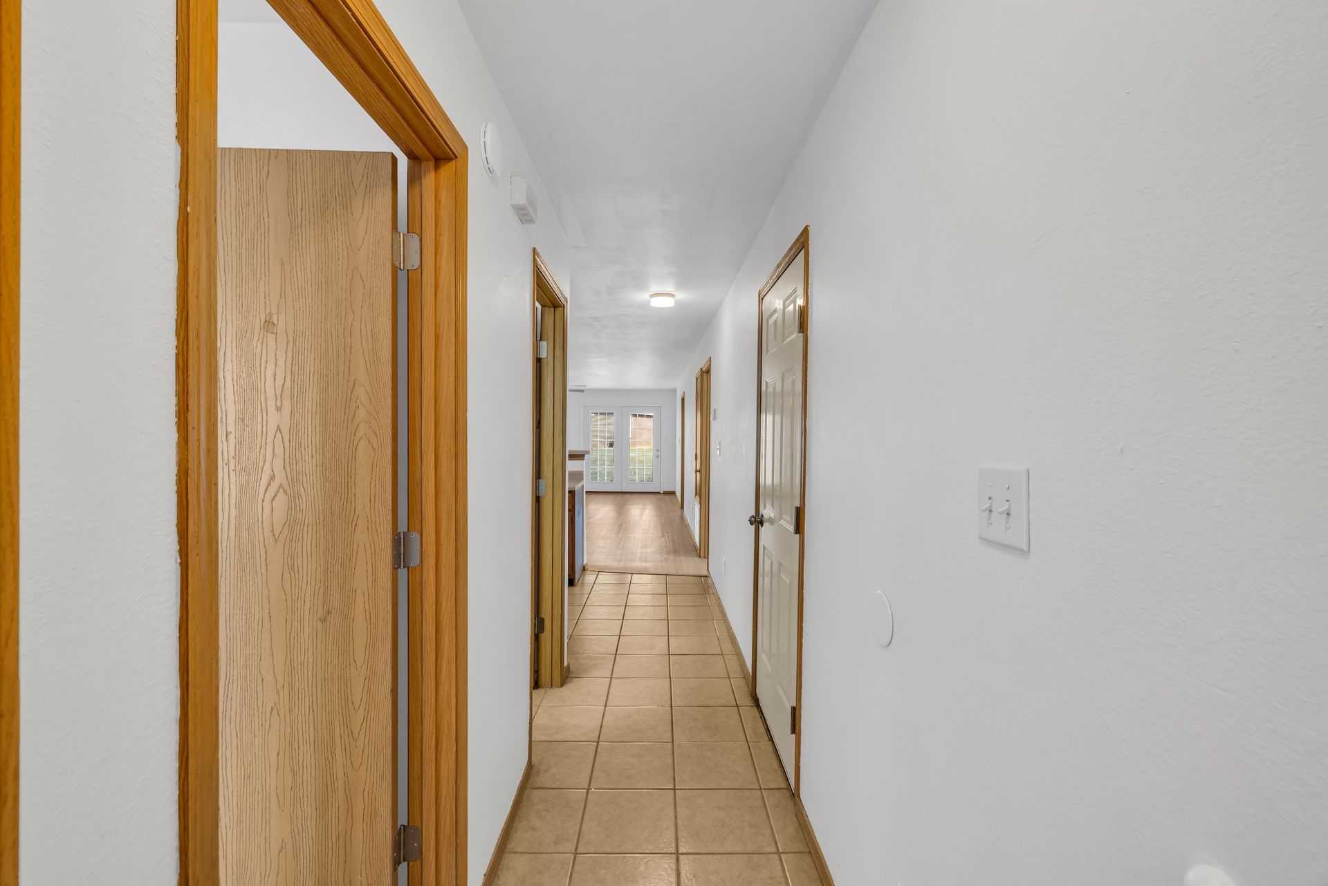 A long hallway with wooden doors leading to different rooms in a house.