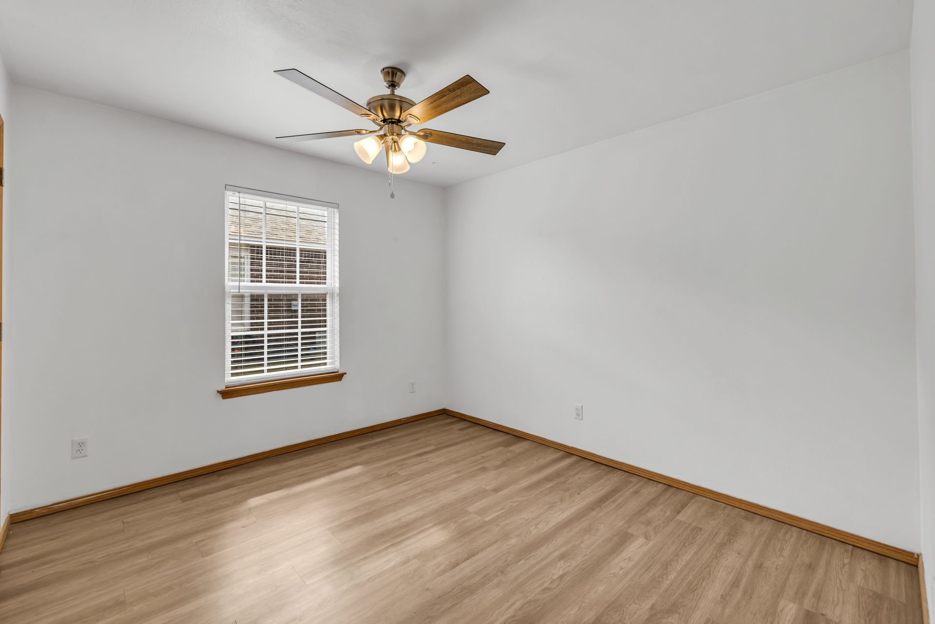 An empty bedroom with a ceiling fan and a window.