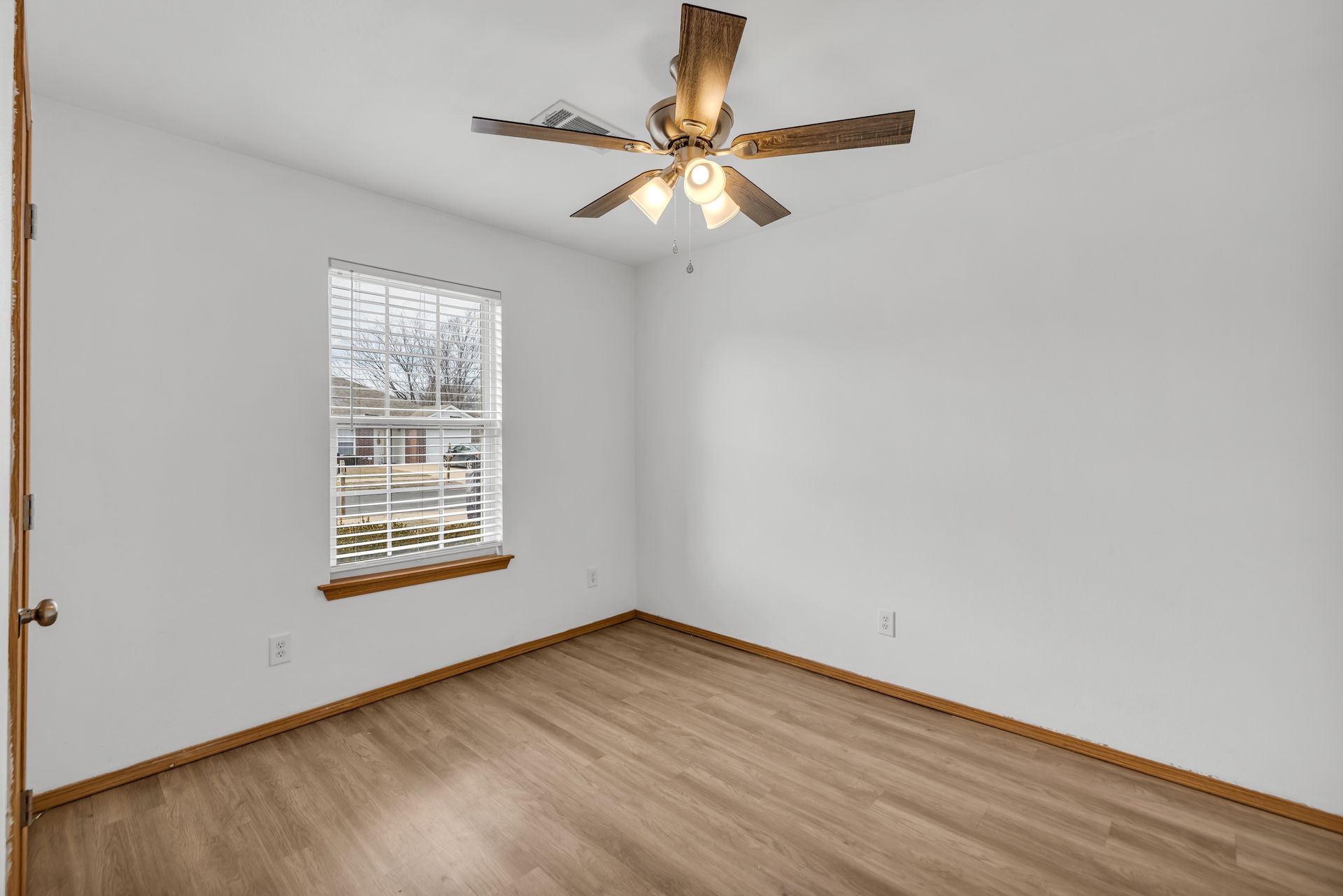 An empty bedroom with a ceiling fan and a window.