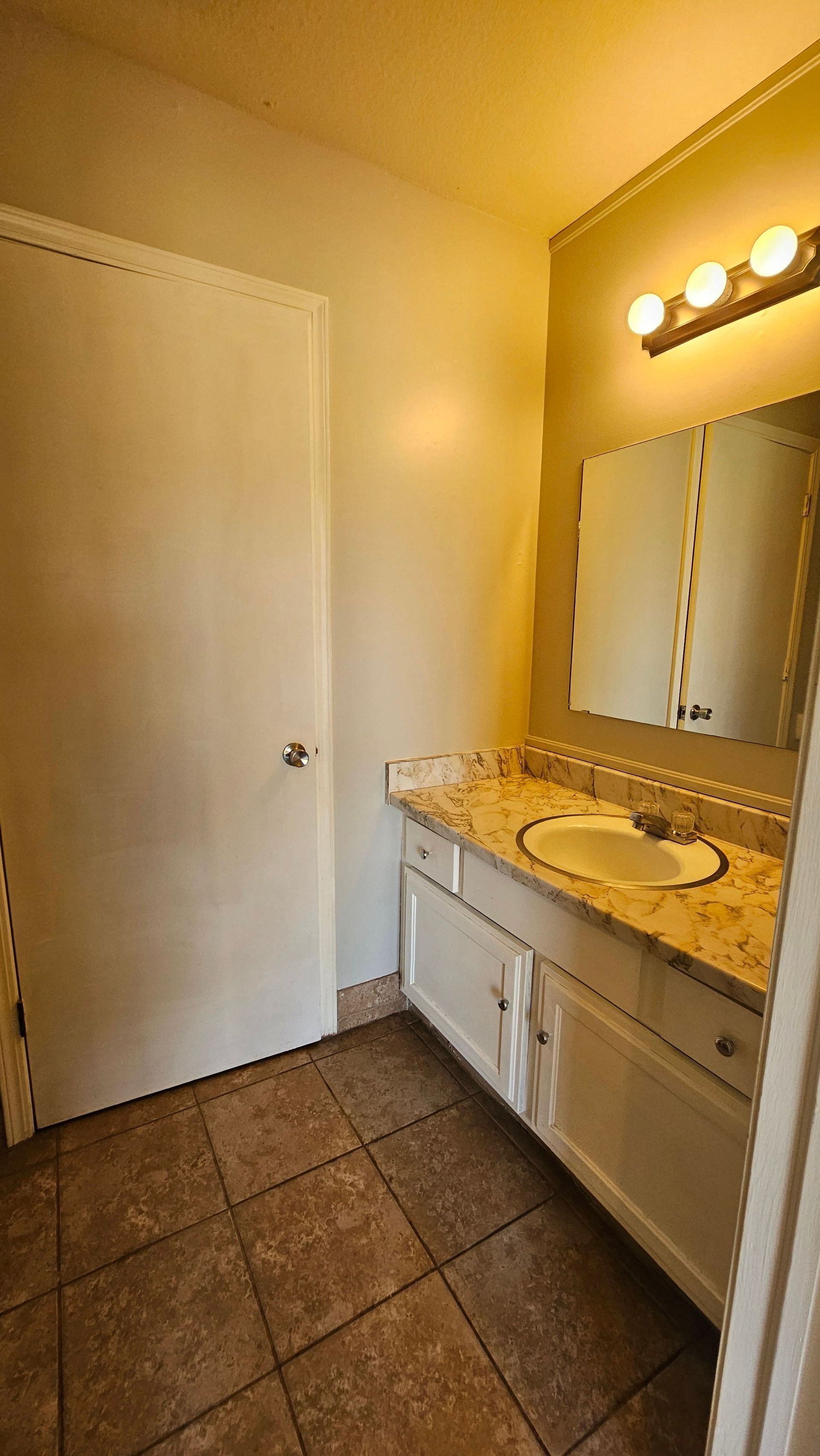 A bathroom with a sink , mirror and tile floor.
