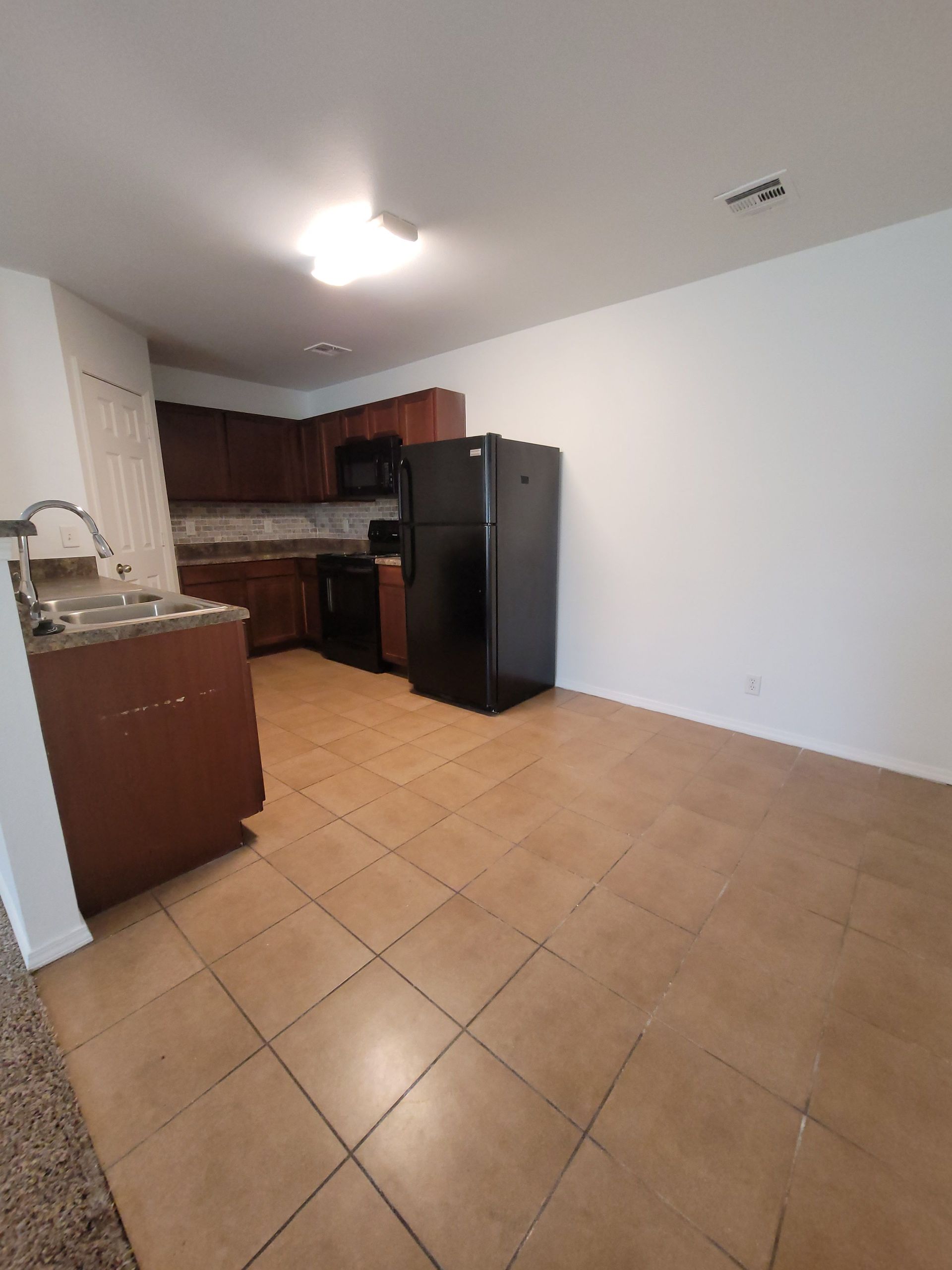 A kitchen with a refrigerator , sink , stove and microwave.