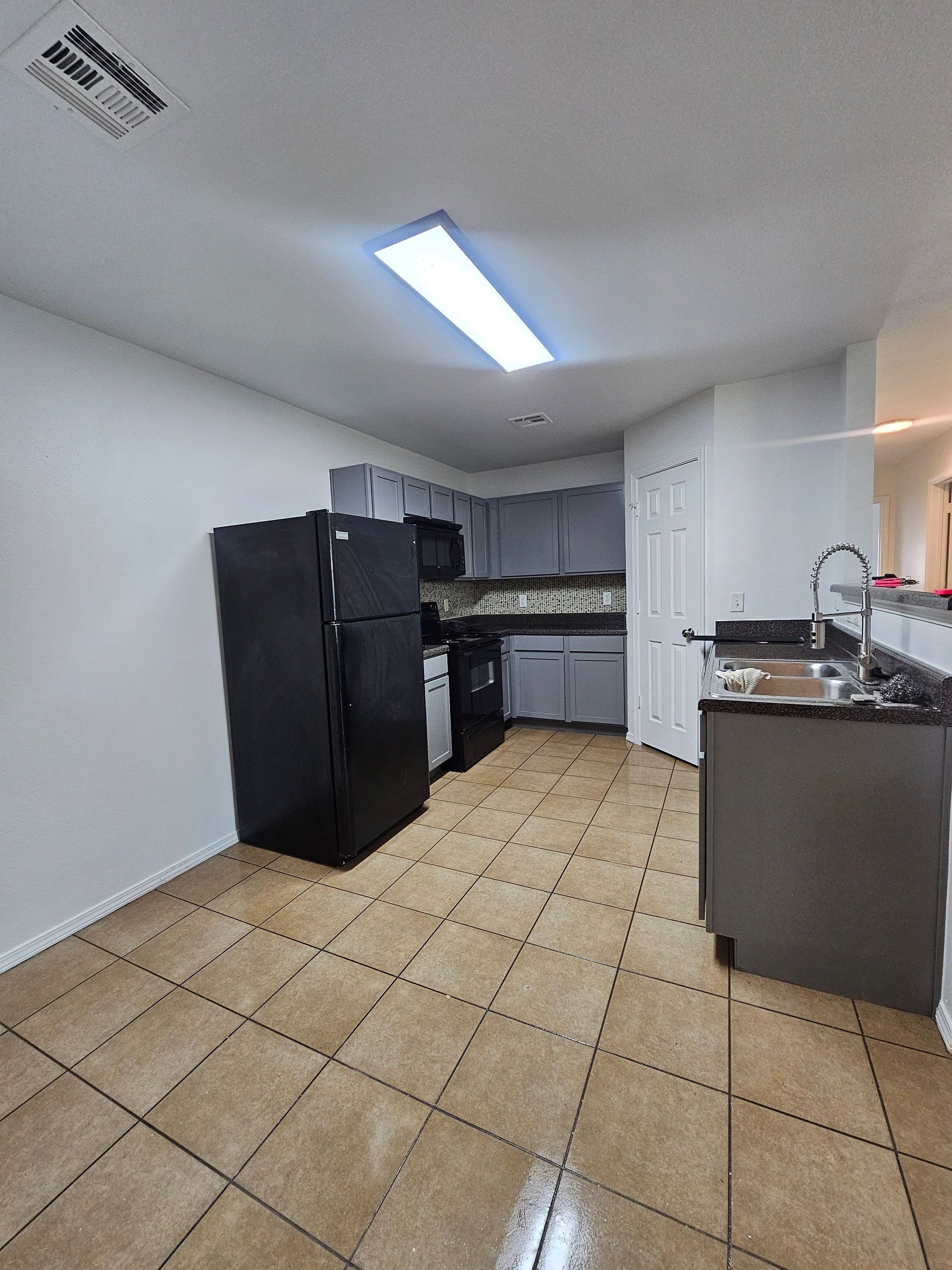A kitchen with a black refrigerator , stove , sink and dishwasher.