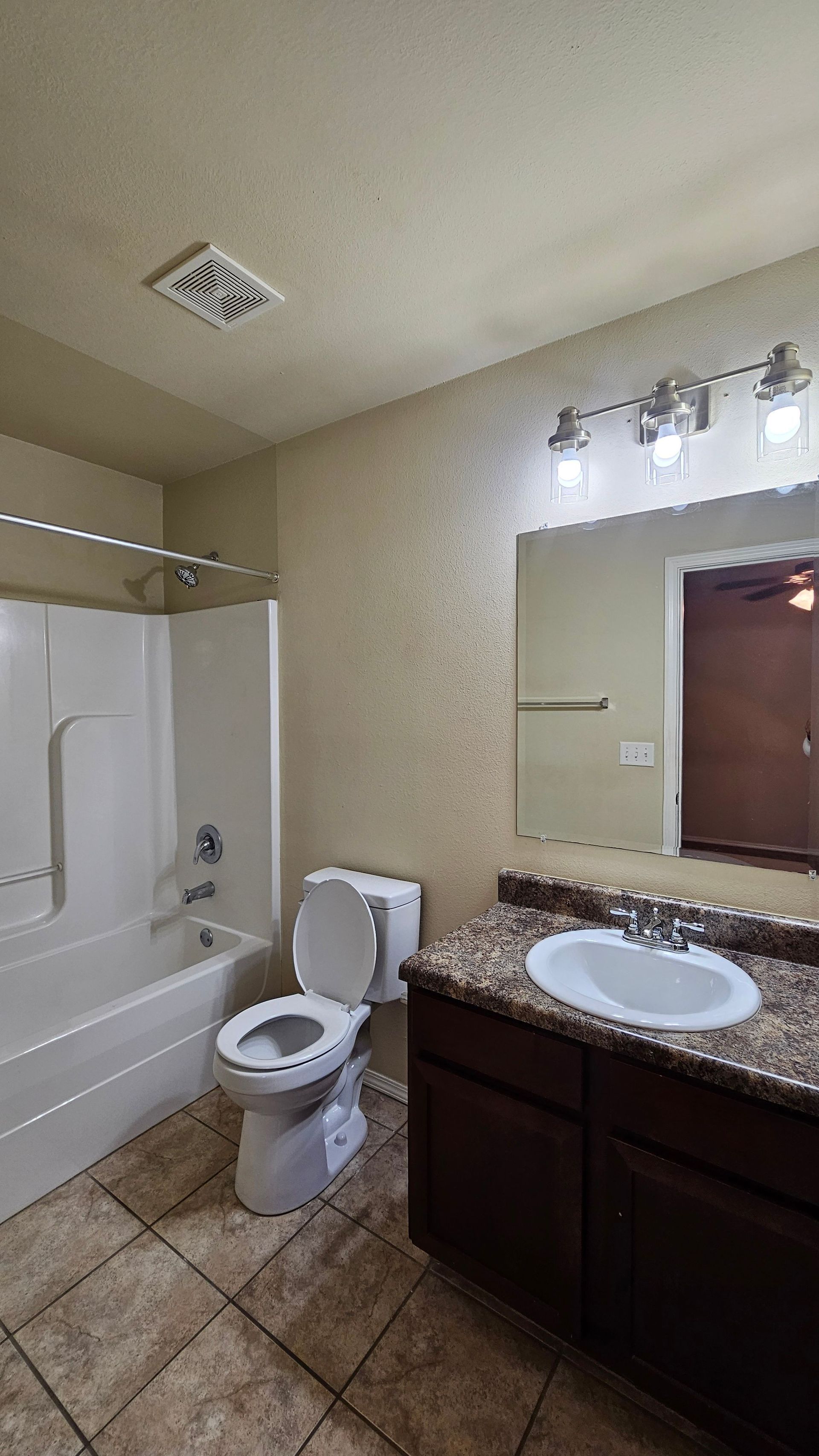 A bathroom with a toilet , sink , bathtub and mirror.