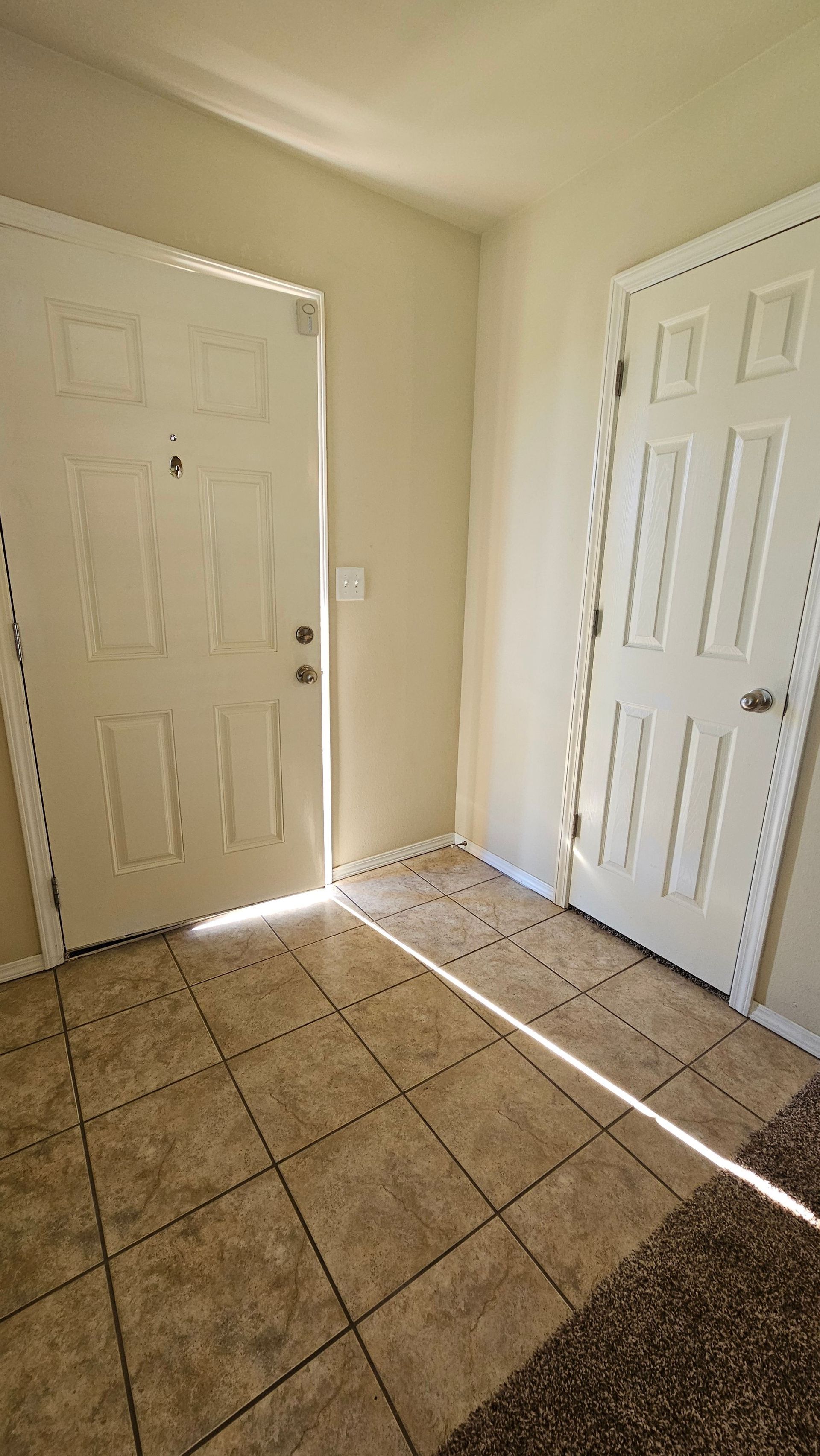 A hallway with two white doors and a tiled floor.