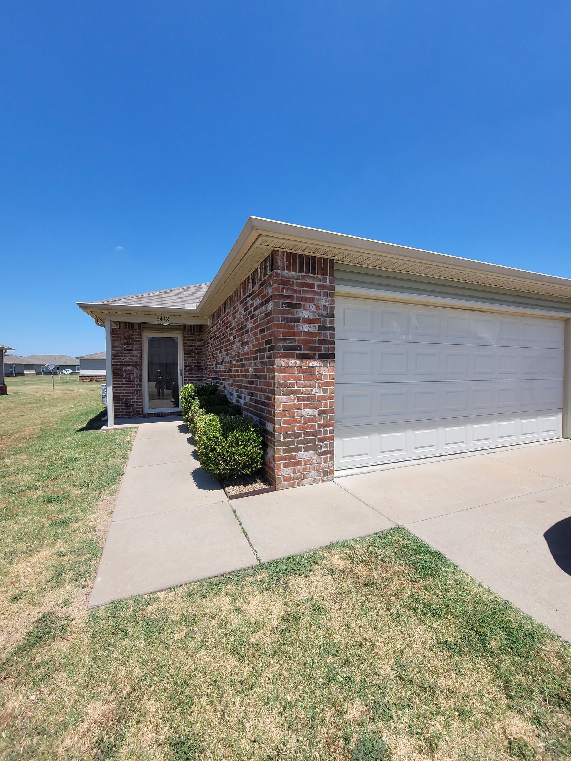 A brick house with a white garage door and a walkway leading to it.