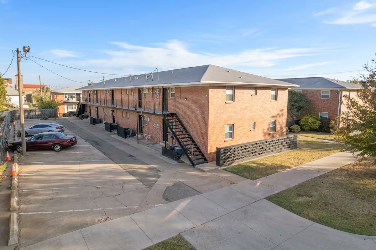 An aerial view of a brick apartment building with cars parked in front of it.