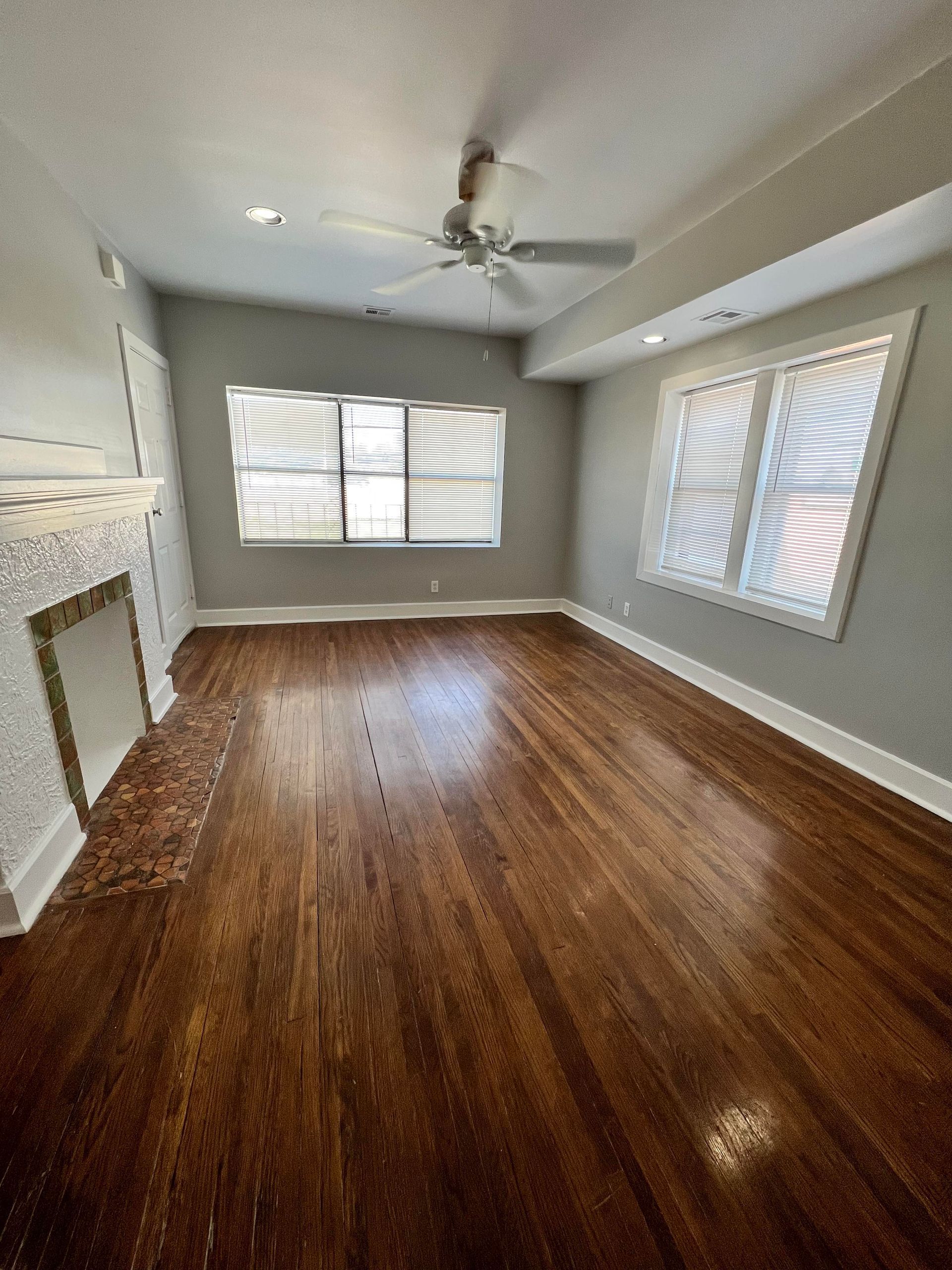 An empty living room with hardwood floors and a ceiling fan.