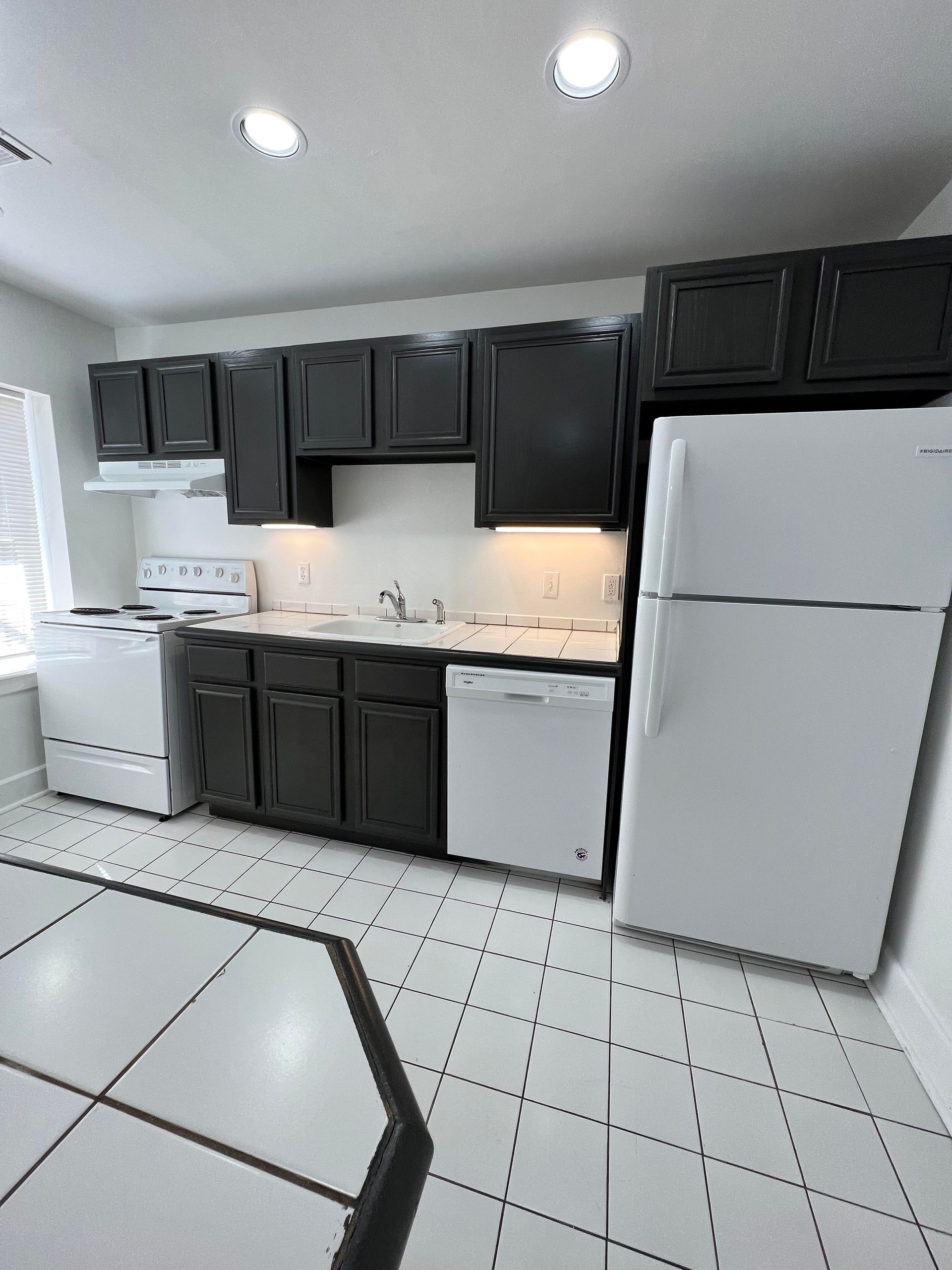 A kitchen with black cabinets and white appliances