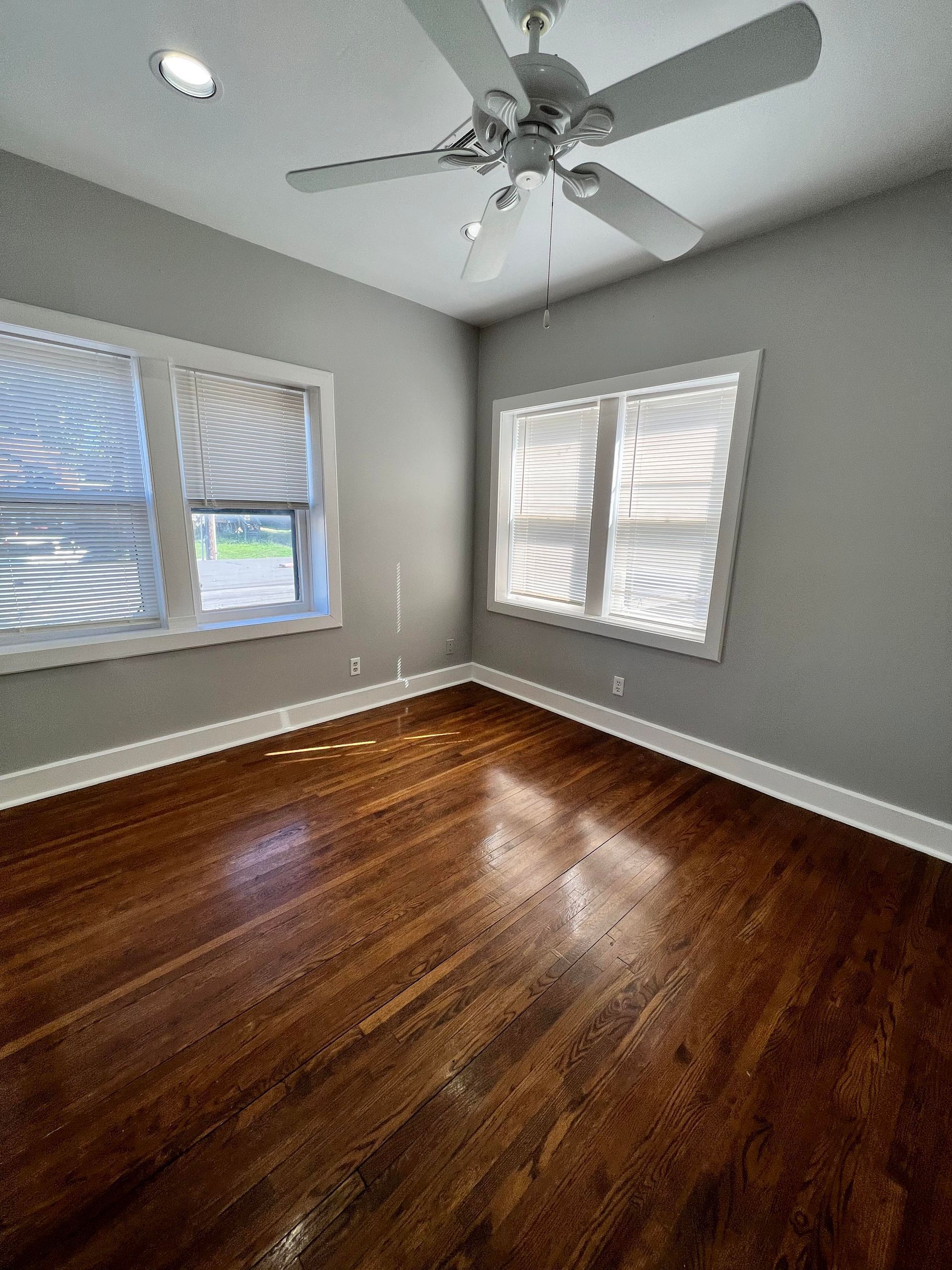 An empty room with hardwood floors and a ceiling fan.