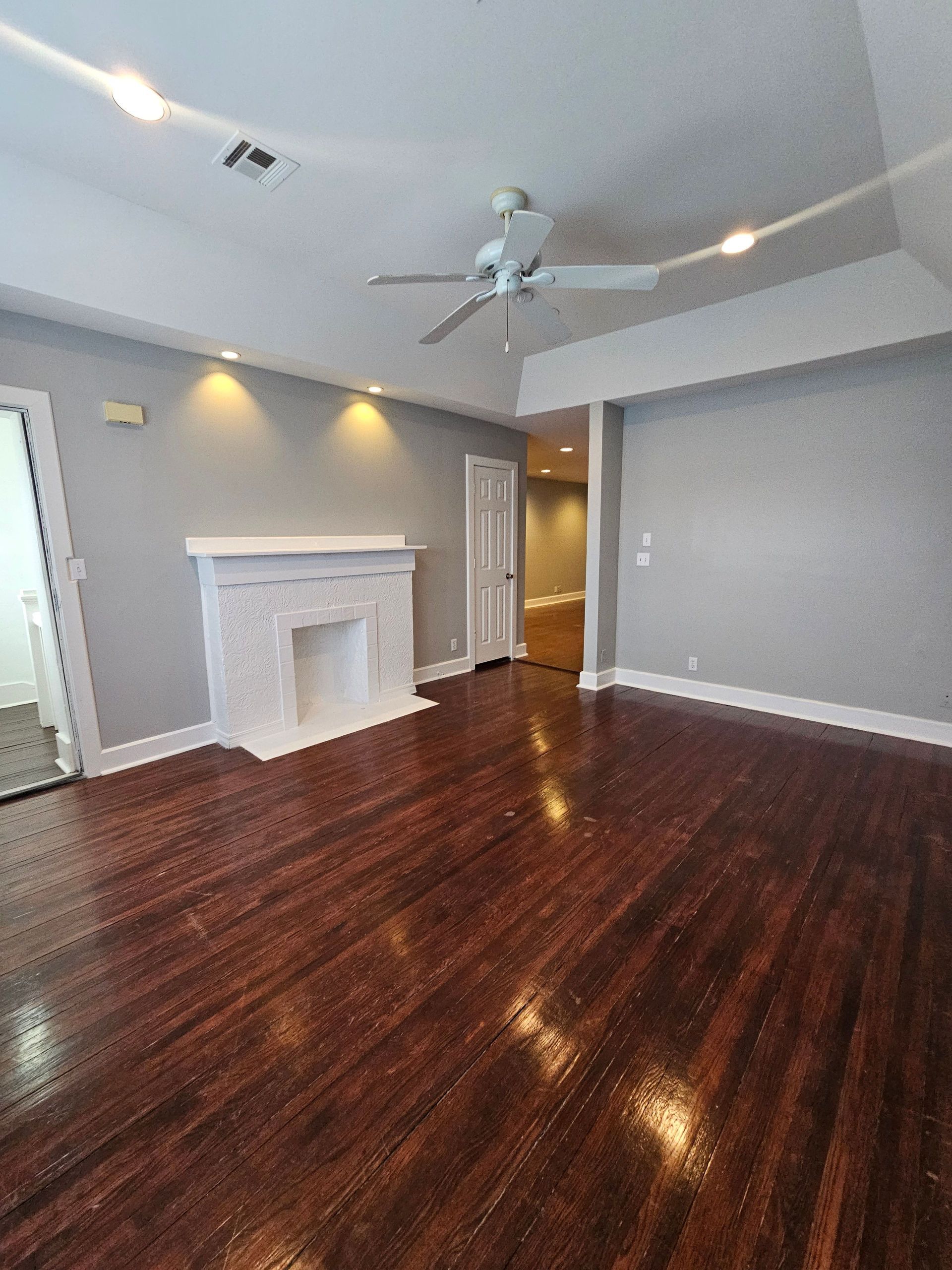 An empty living room with a fireplace and a ceiling fan.