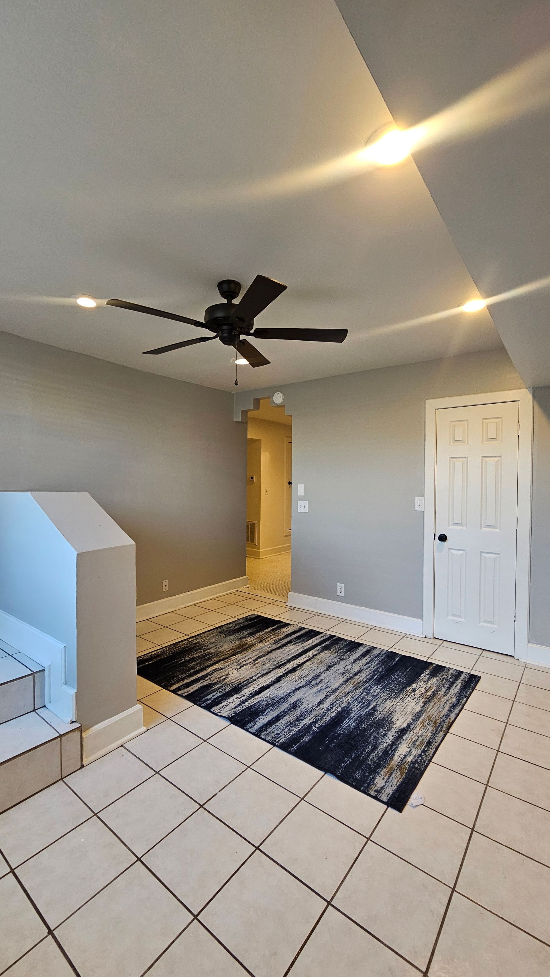A living room with a rug and a ceiling fan.