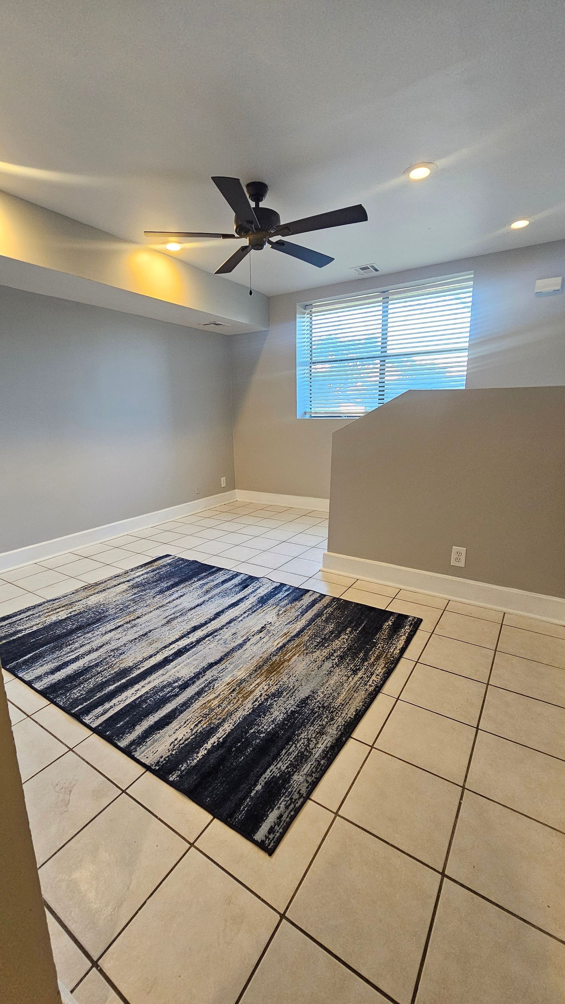 A living room with a rug and a ceiling fan.
