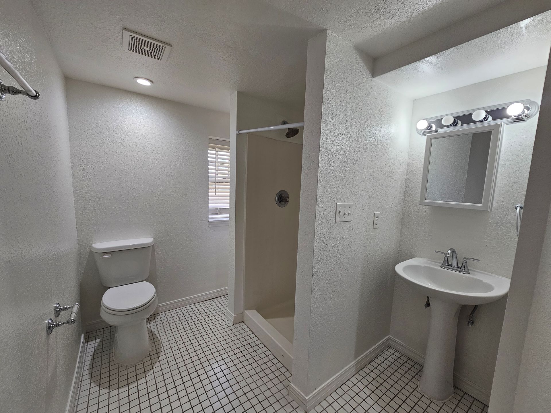 A bathroom with a toilet , sink and shower.