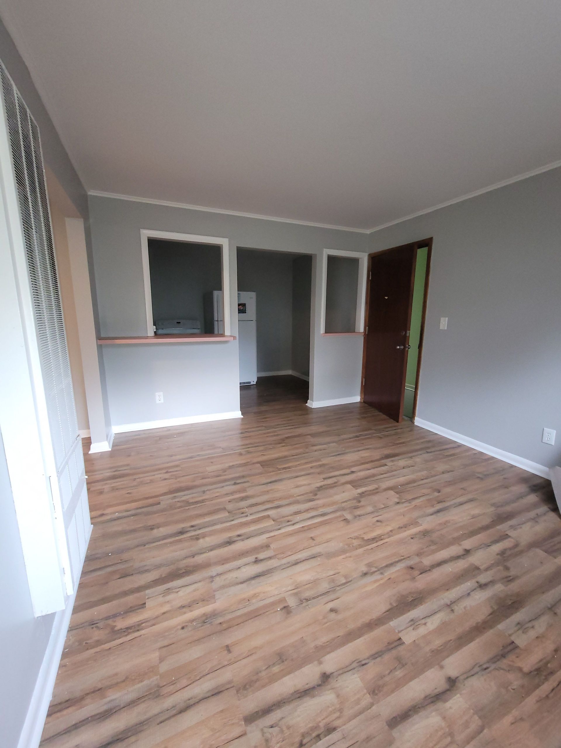 An empty living room with hardwood floors and gray walls.