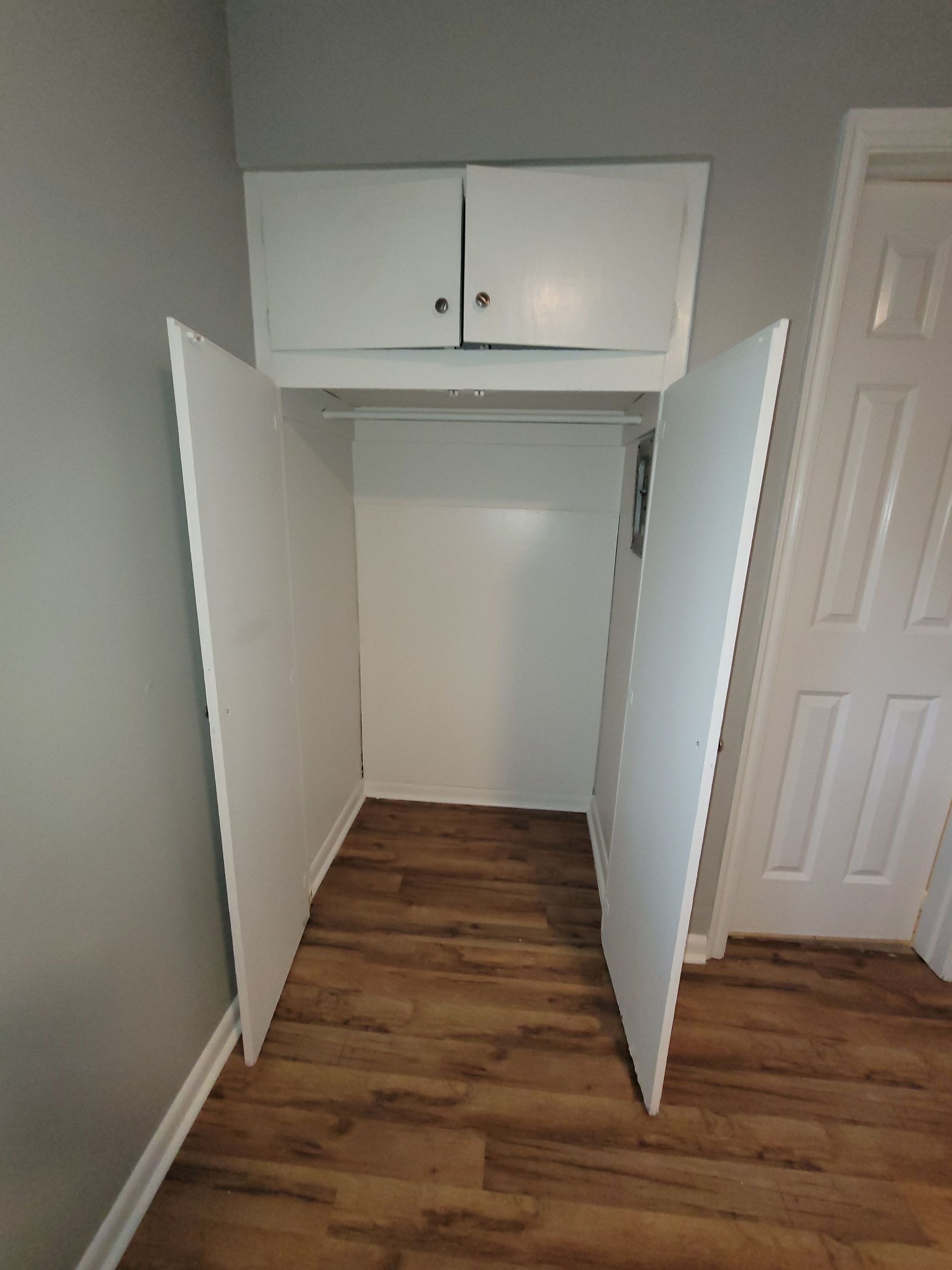 A closet with the doors open in a room with hardwood floors.