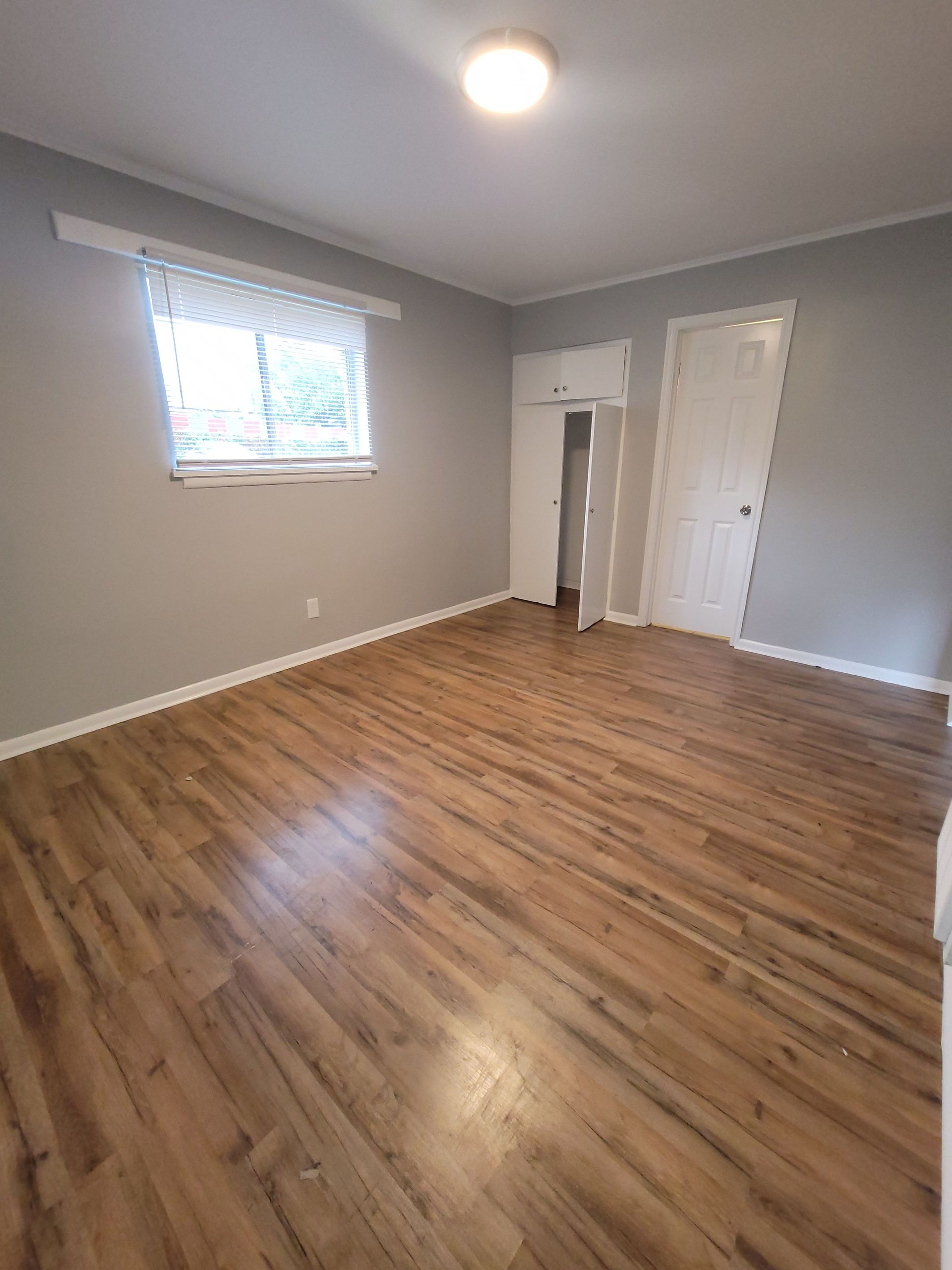 A large empty room with hardwood floors and a window.