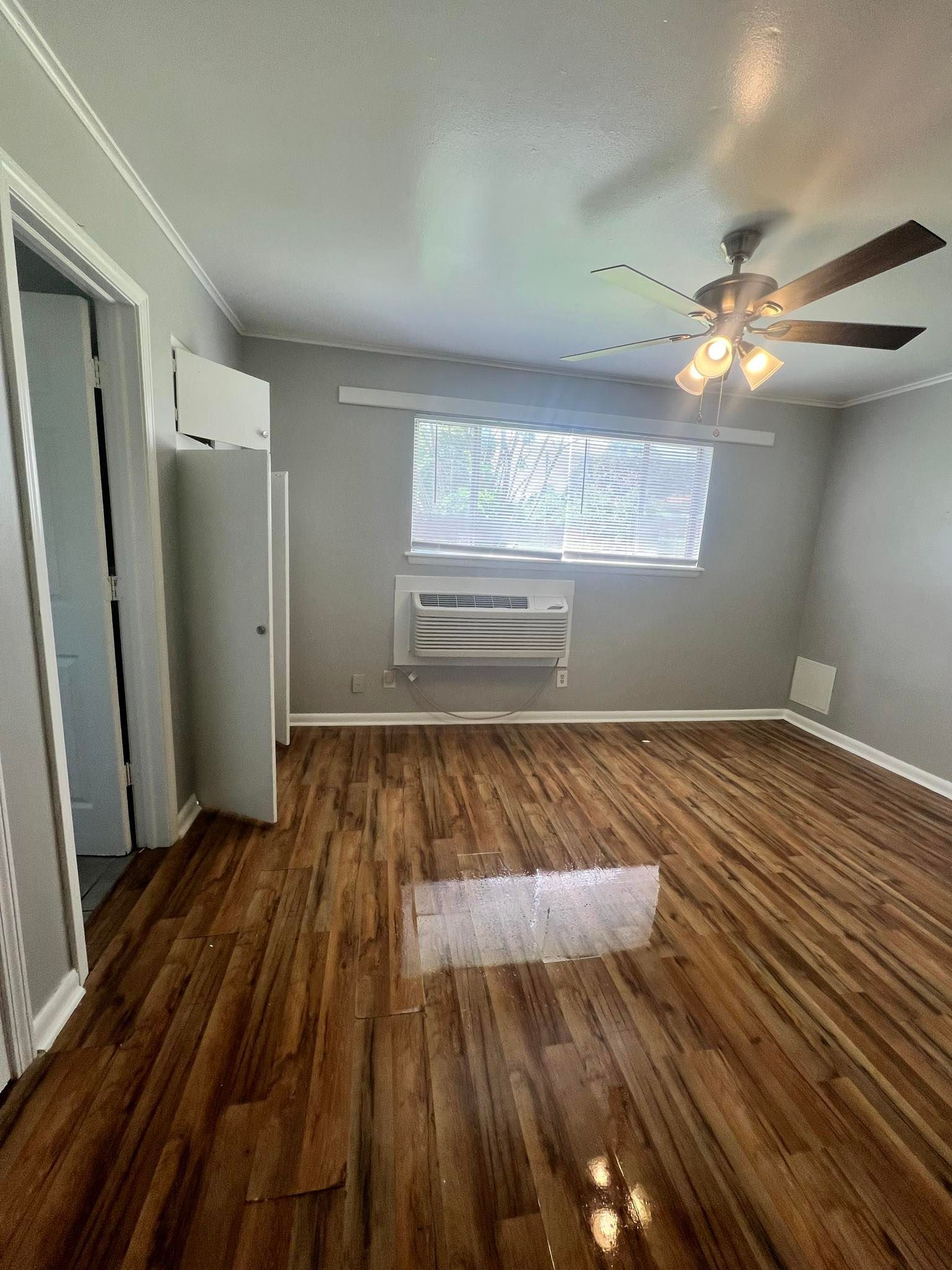 An empty living room with hardwood floors and a ceiling fan.