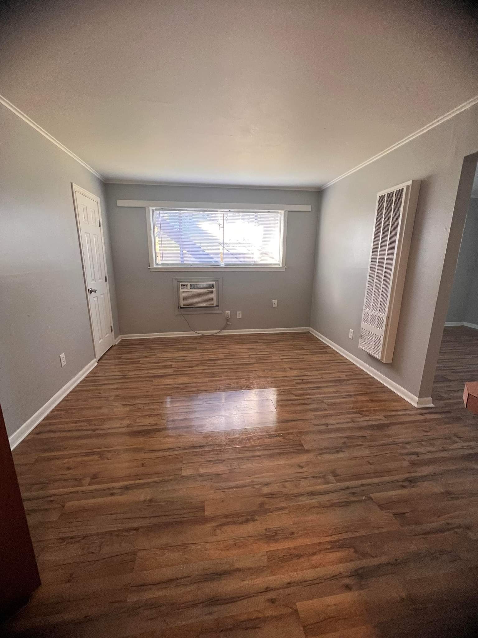 An empty living room with hardwood floors and a window.