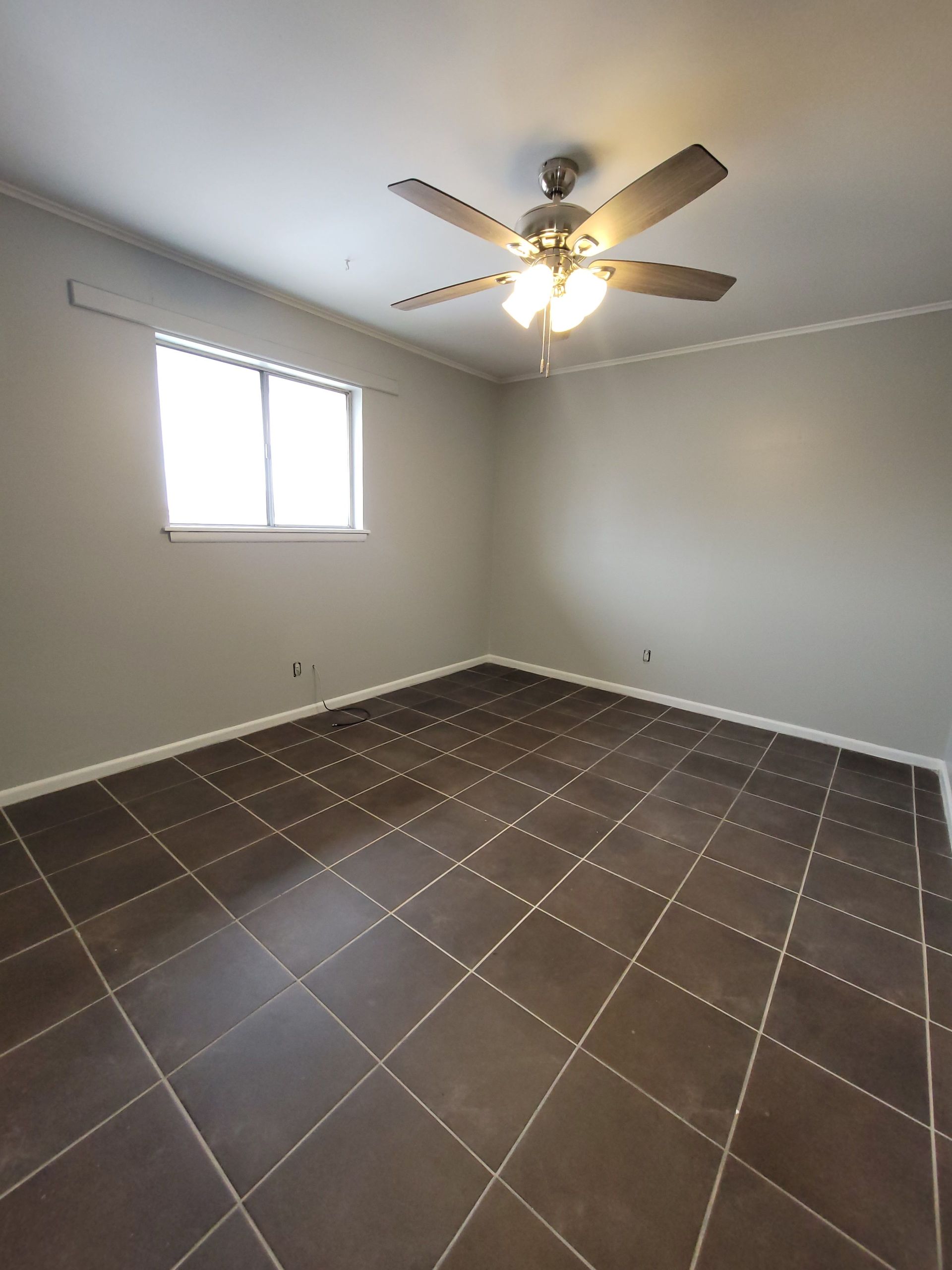 An empty room with a ceiling fan and a window