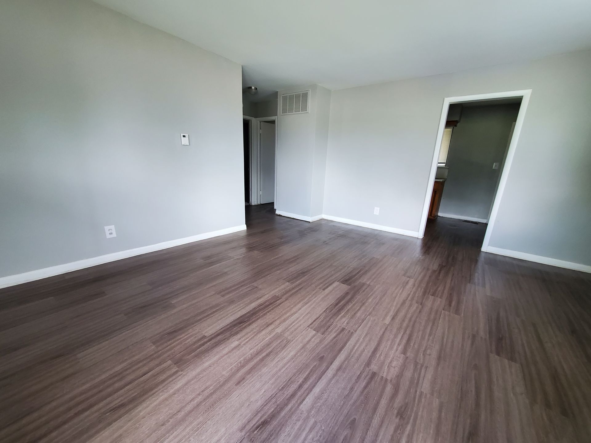 An empty living room with hardwood floors and white walls.