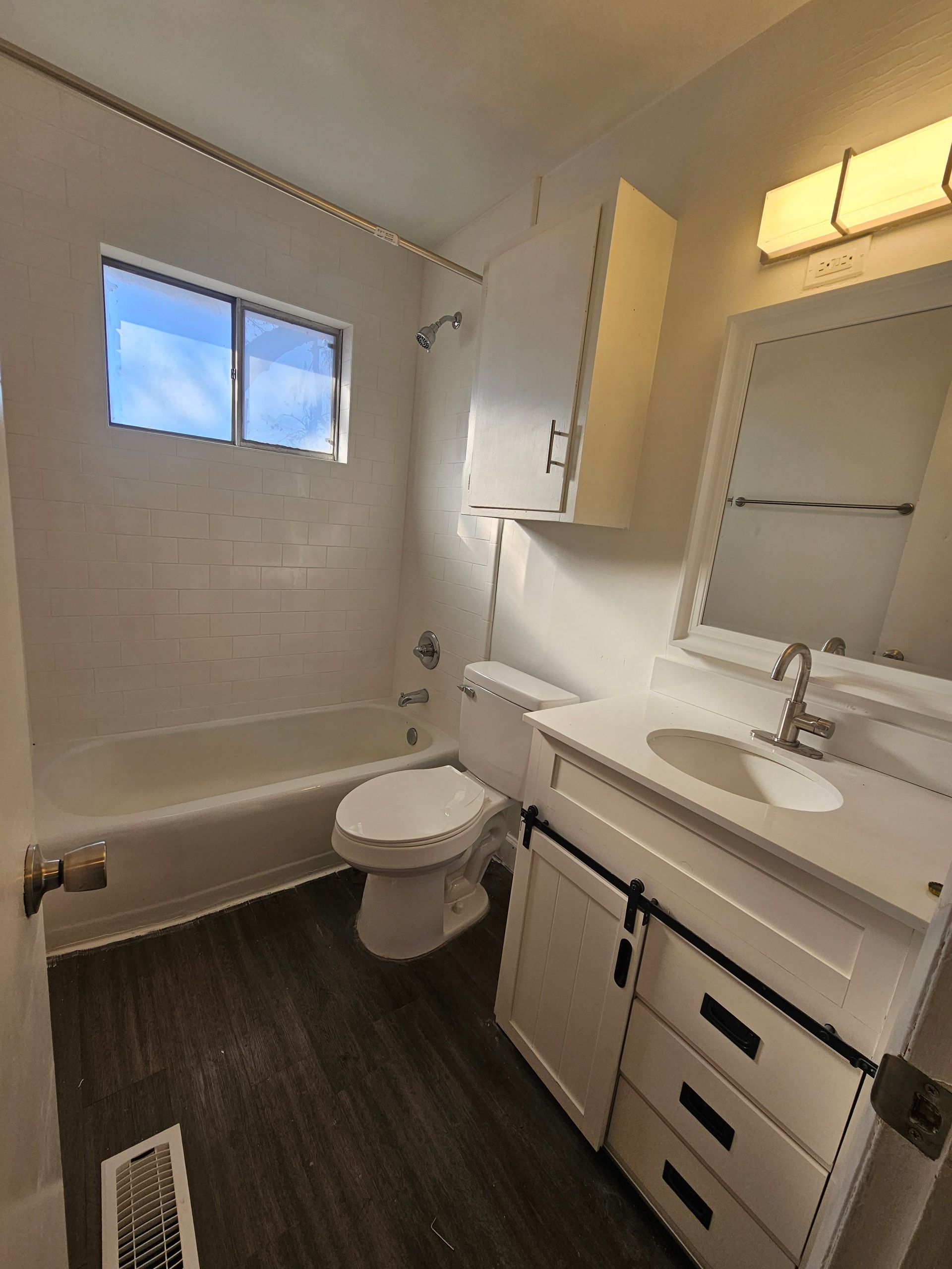 A bathroom with a toilet , sink , tub and mirror.