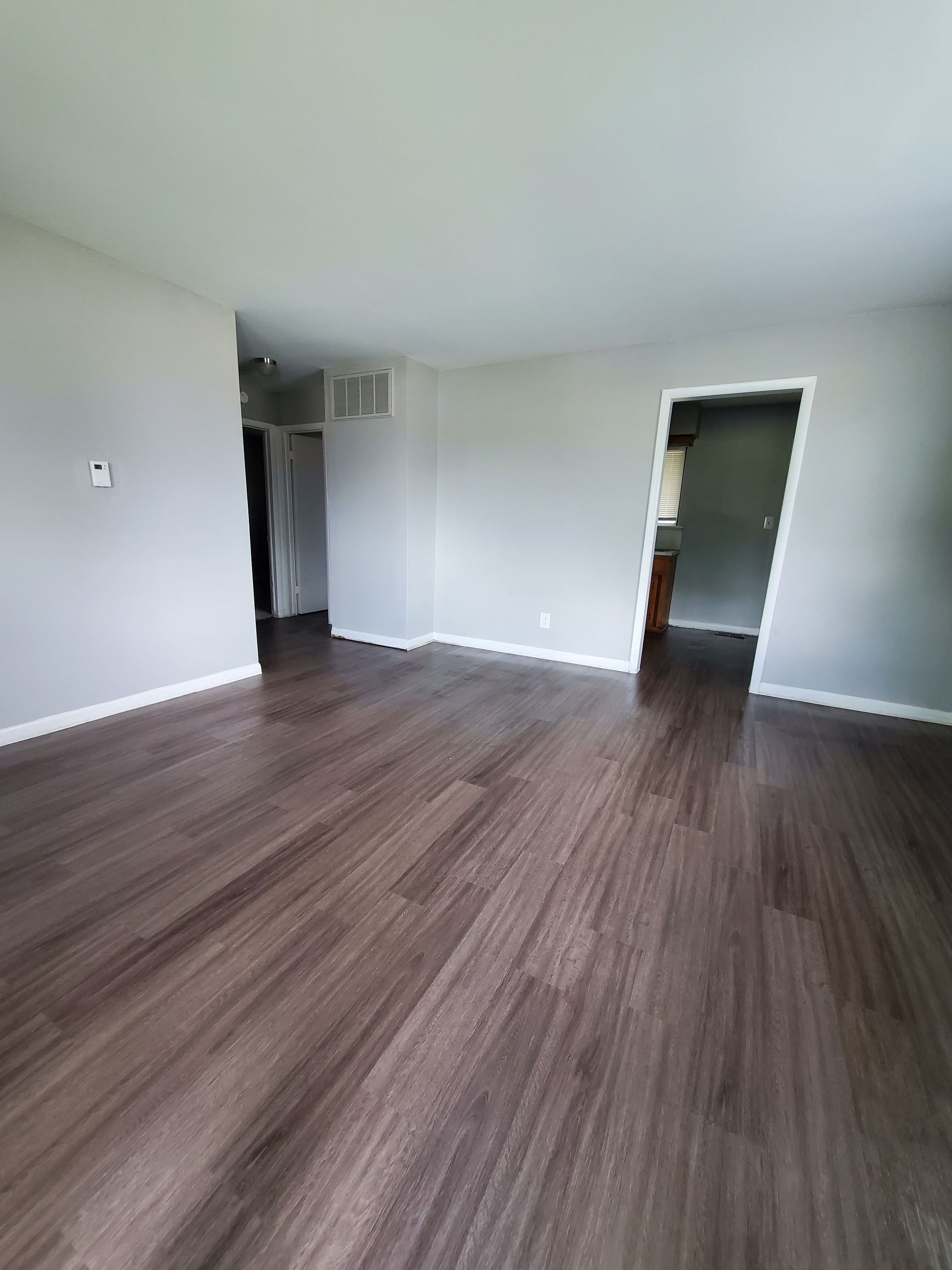 An empty living room with hardwood floors and white walls.