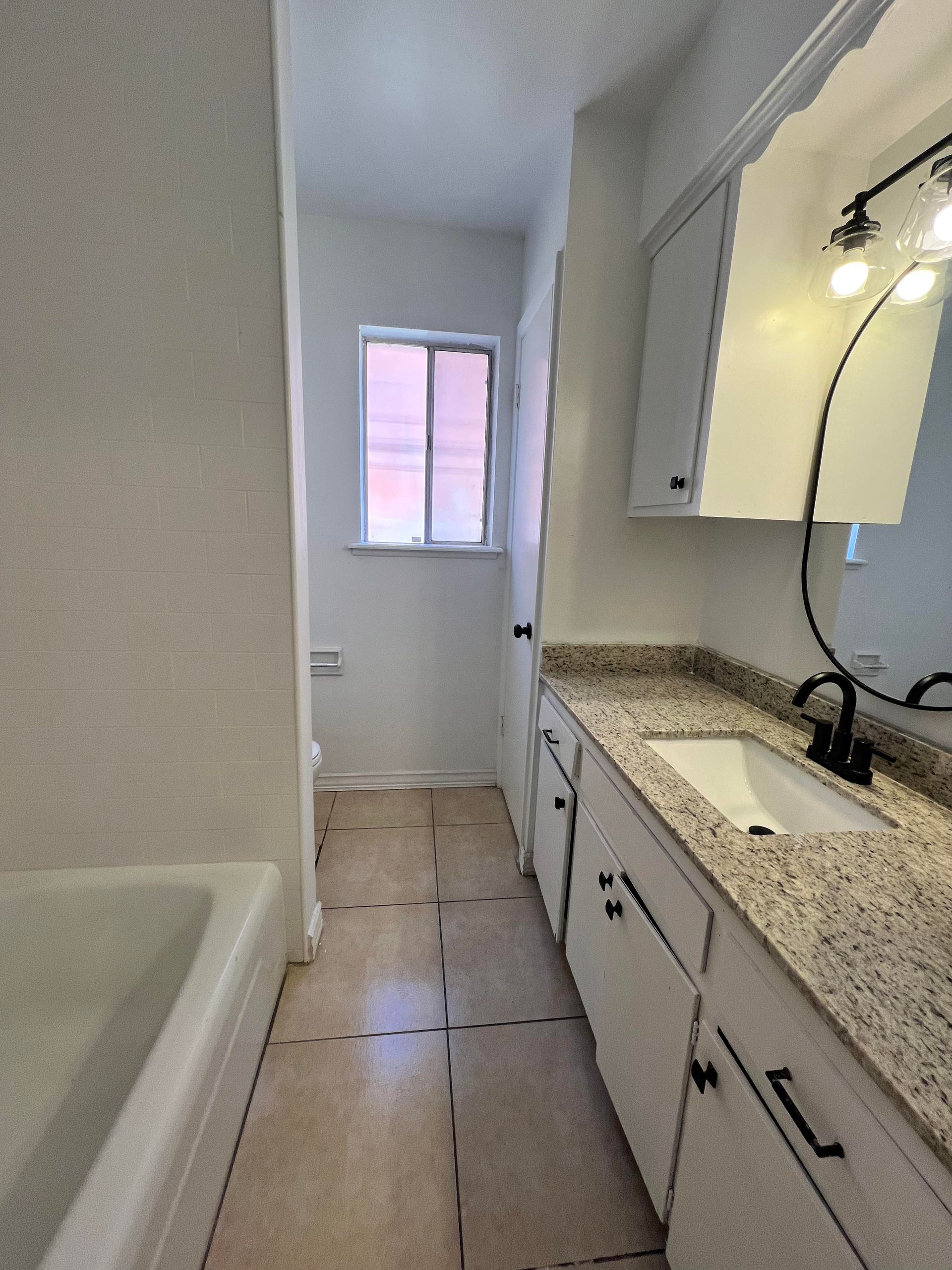 A bathroom with a tub , sink and mirror