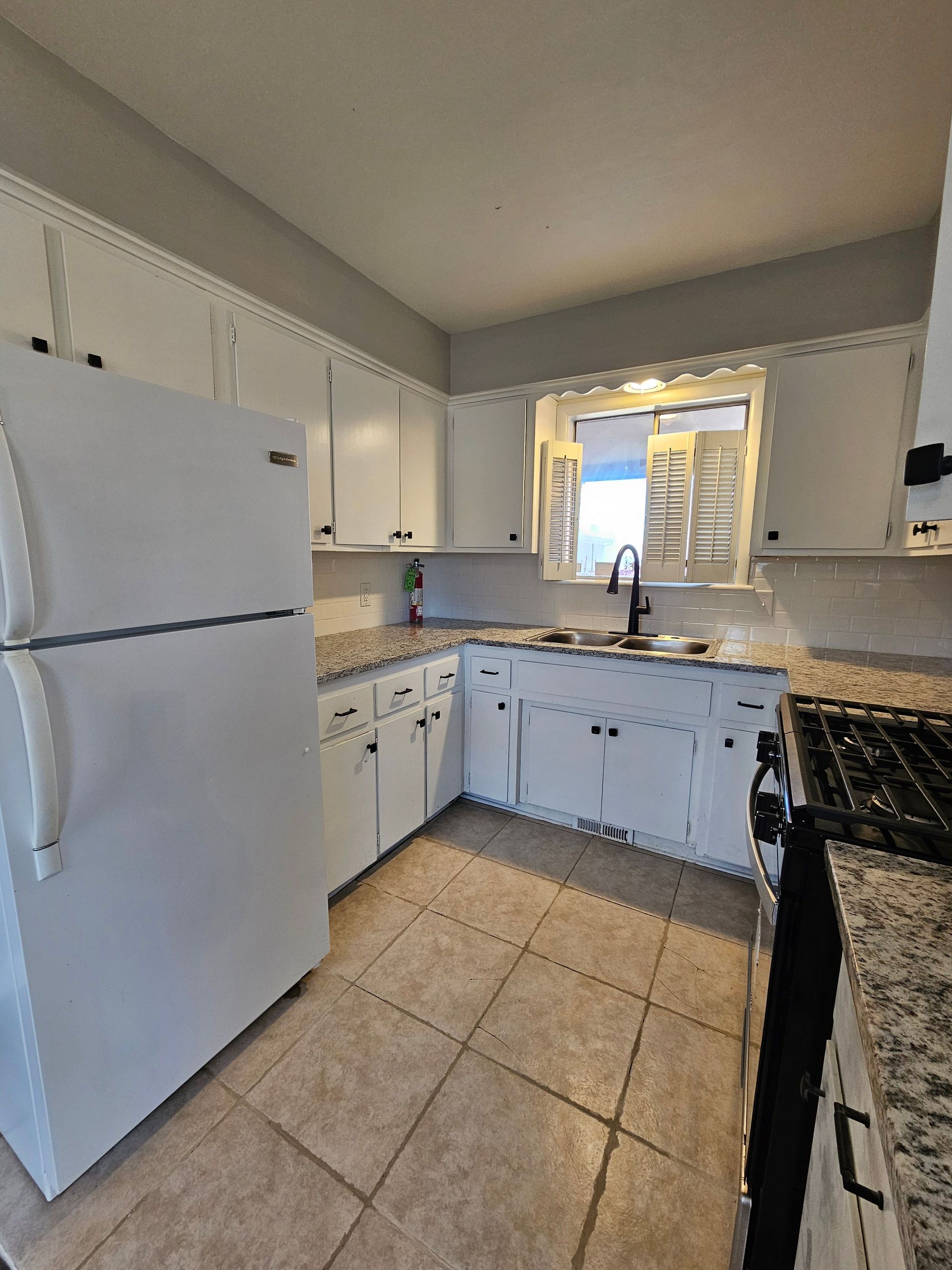 A kitchen with white cabinets and a white refrigerator