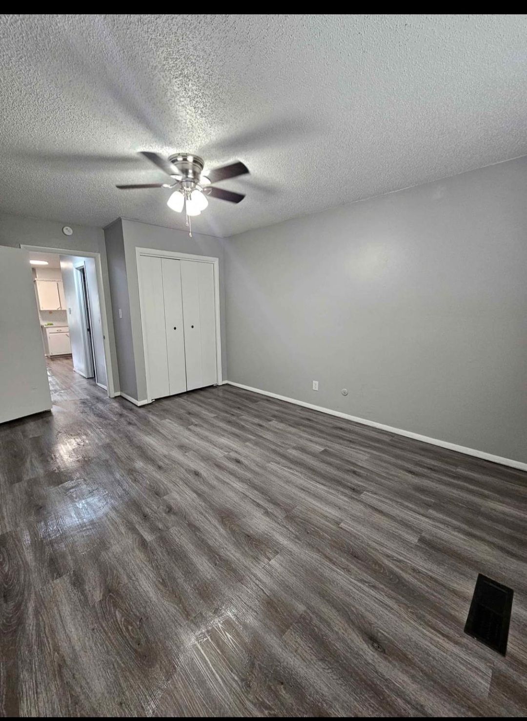 A living room with hardwood floors and a ceiling fan.
