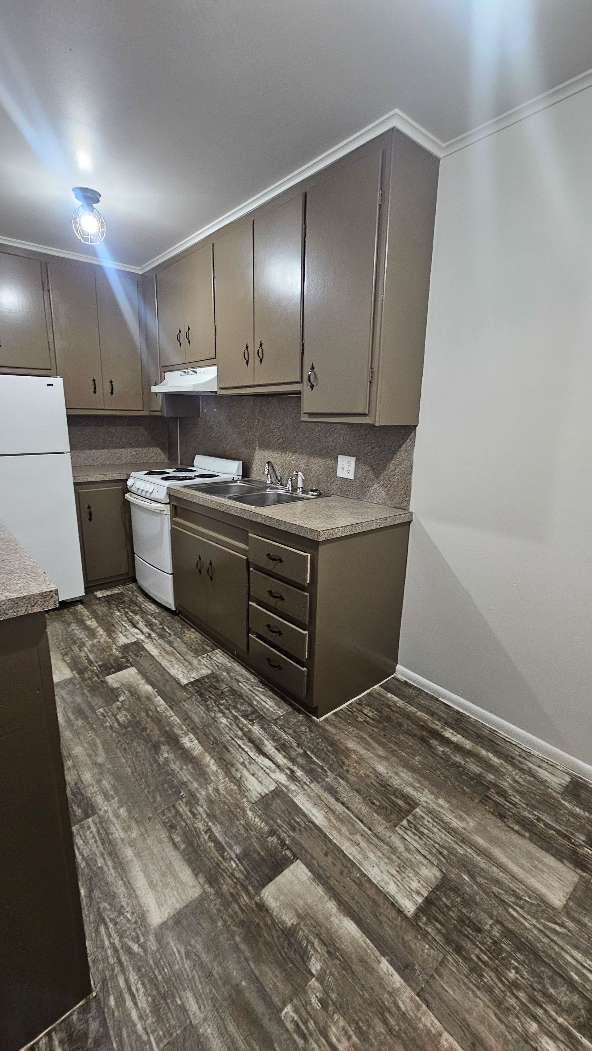 A kitchen with a refrigerator , stove , sink and cabinets.