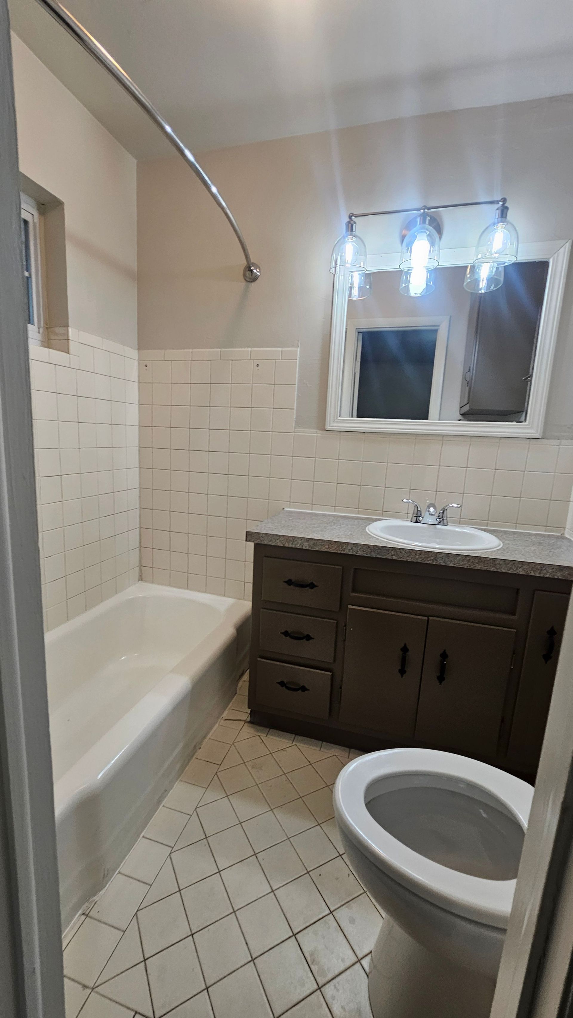 A bathroom with a toilet , sink , bathtub and mirror.