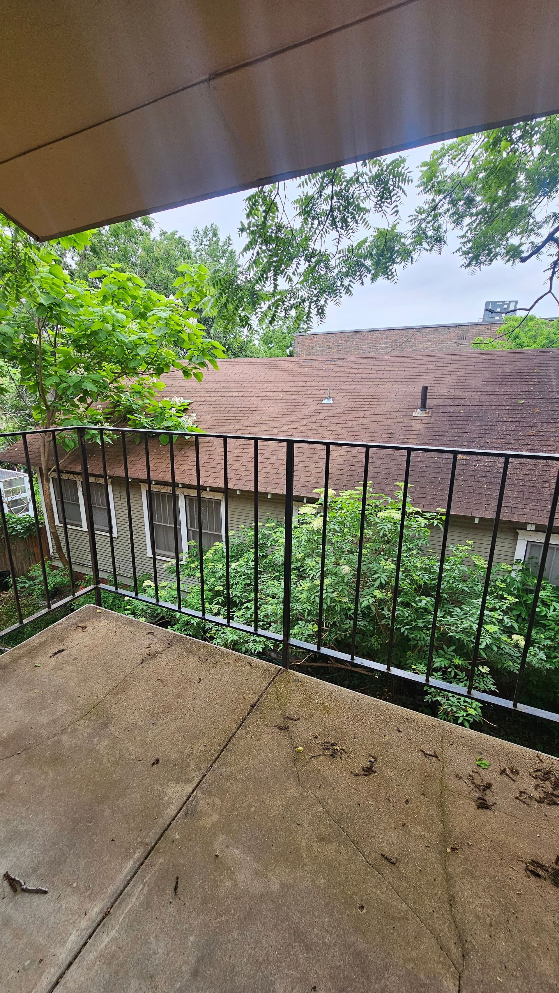 A balcony with a railing and a view of a house and trees.