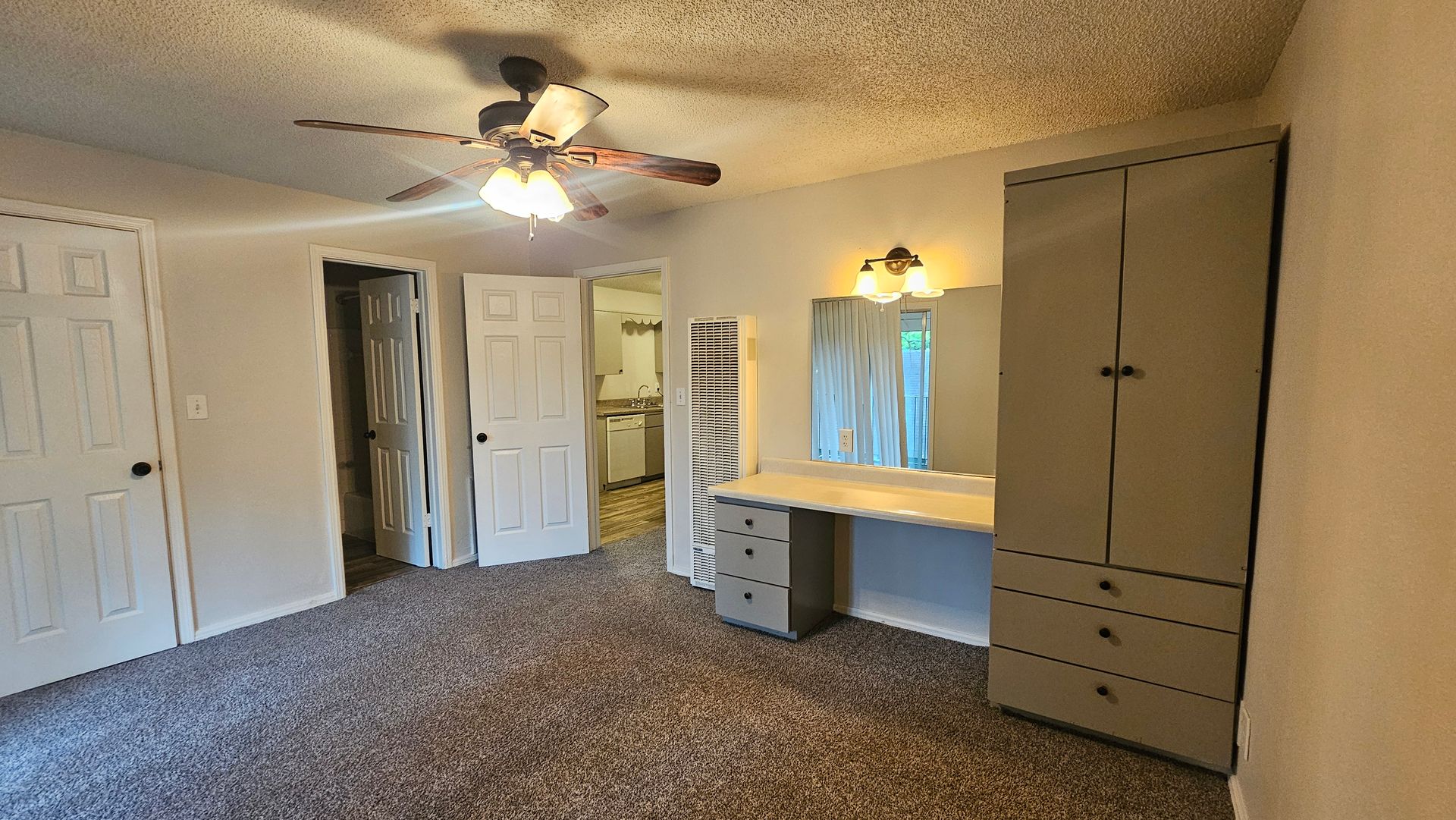 An empty bedroom with a ceiling fan and a mirror.
