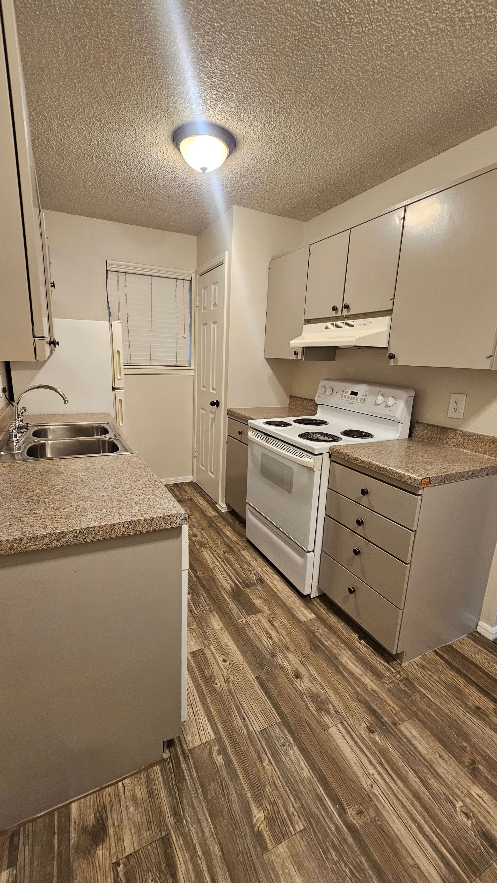 A kitchen with a stove , sink , and cabinets.