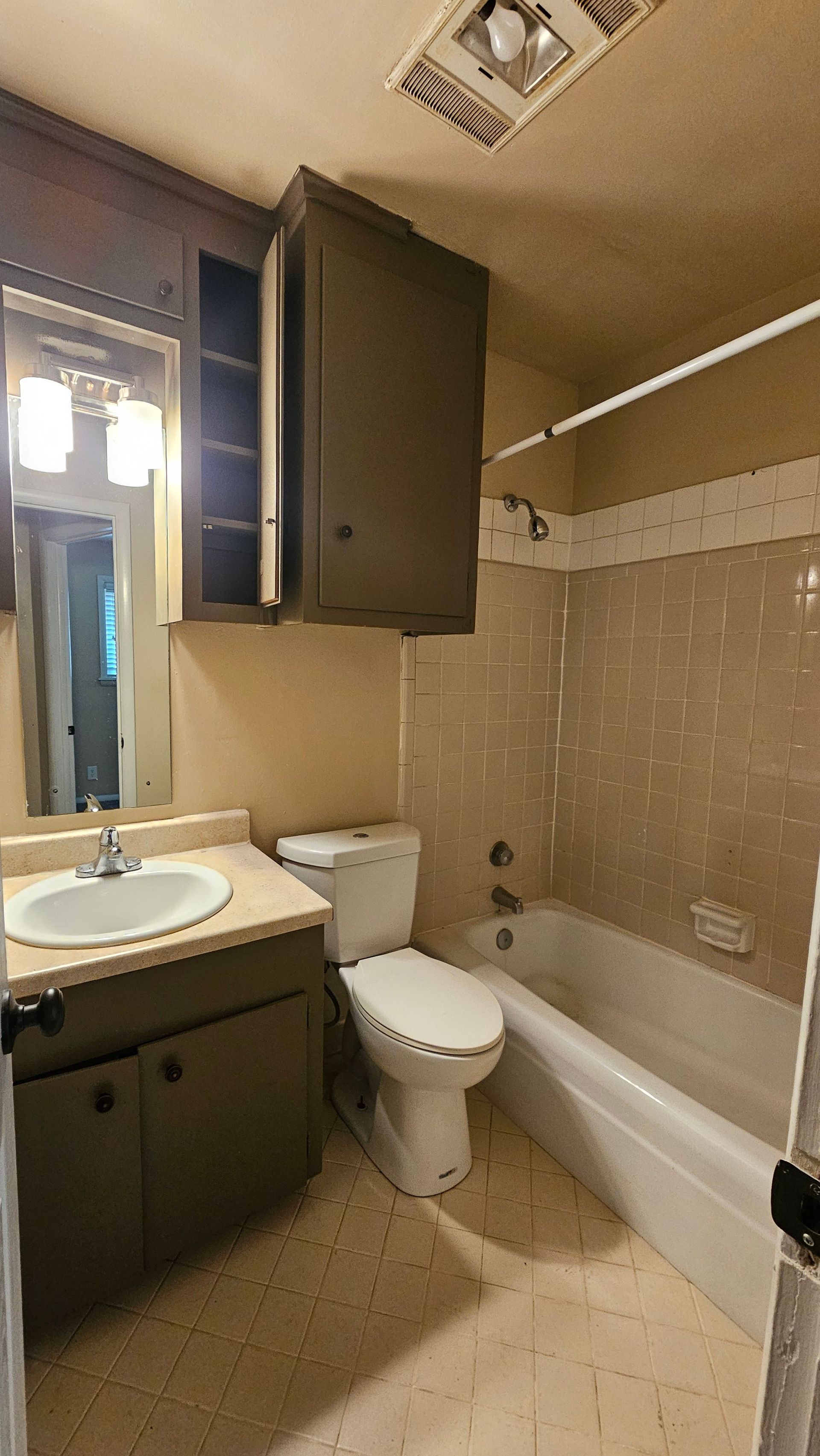 A bathroom with a toilet , sink , tub and mirror.