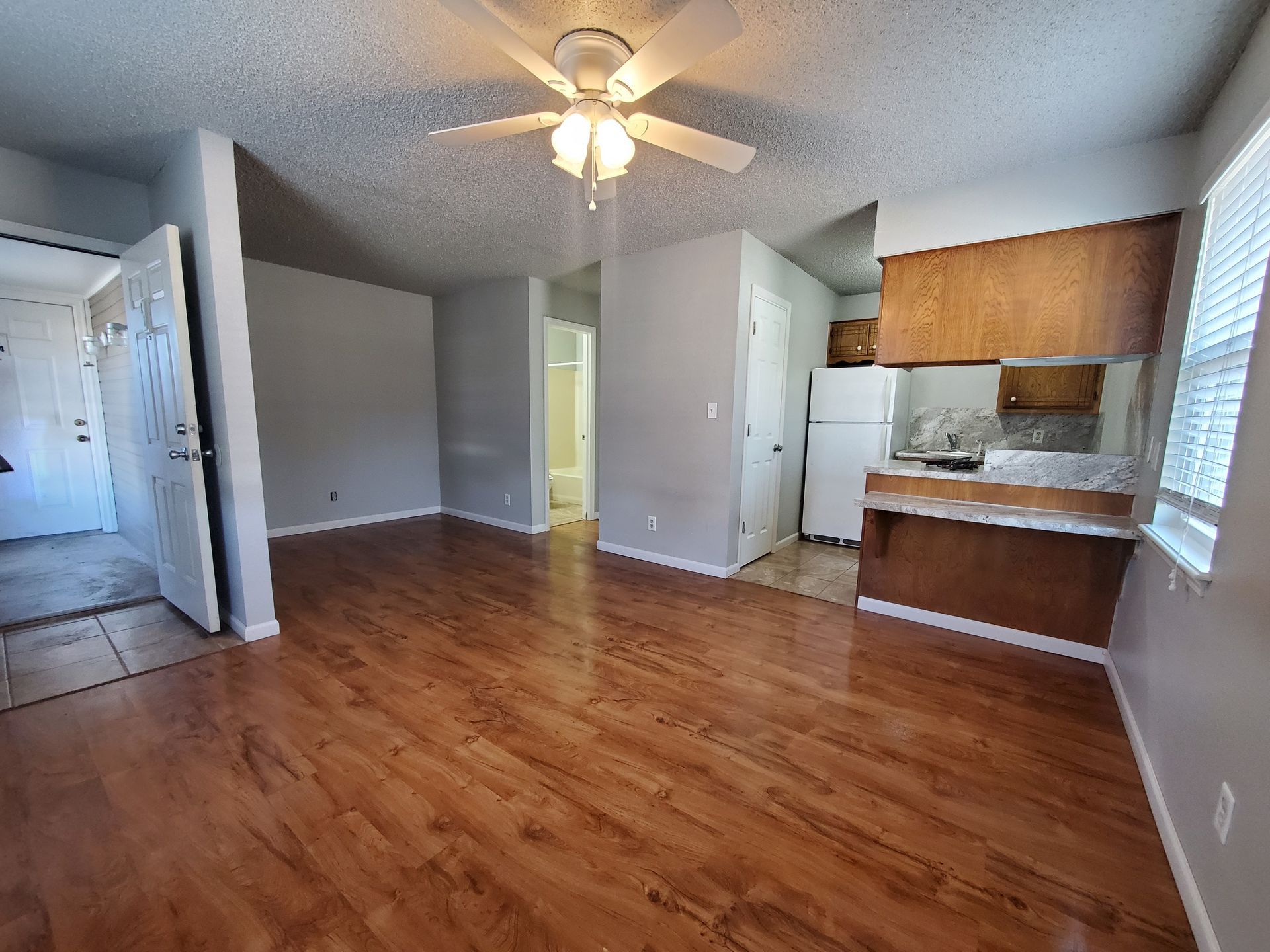 A living room with hardwood floors and a ceiling fan.