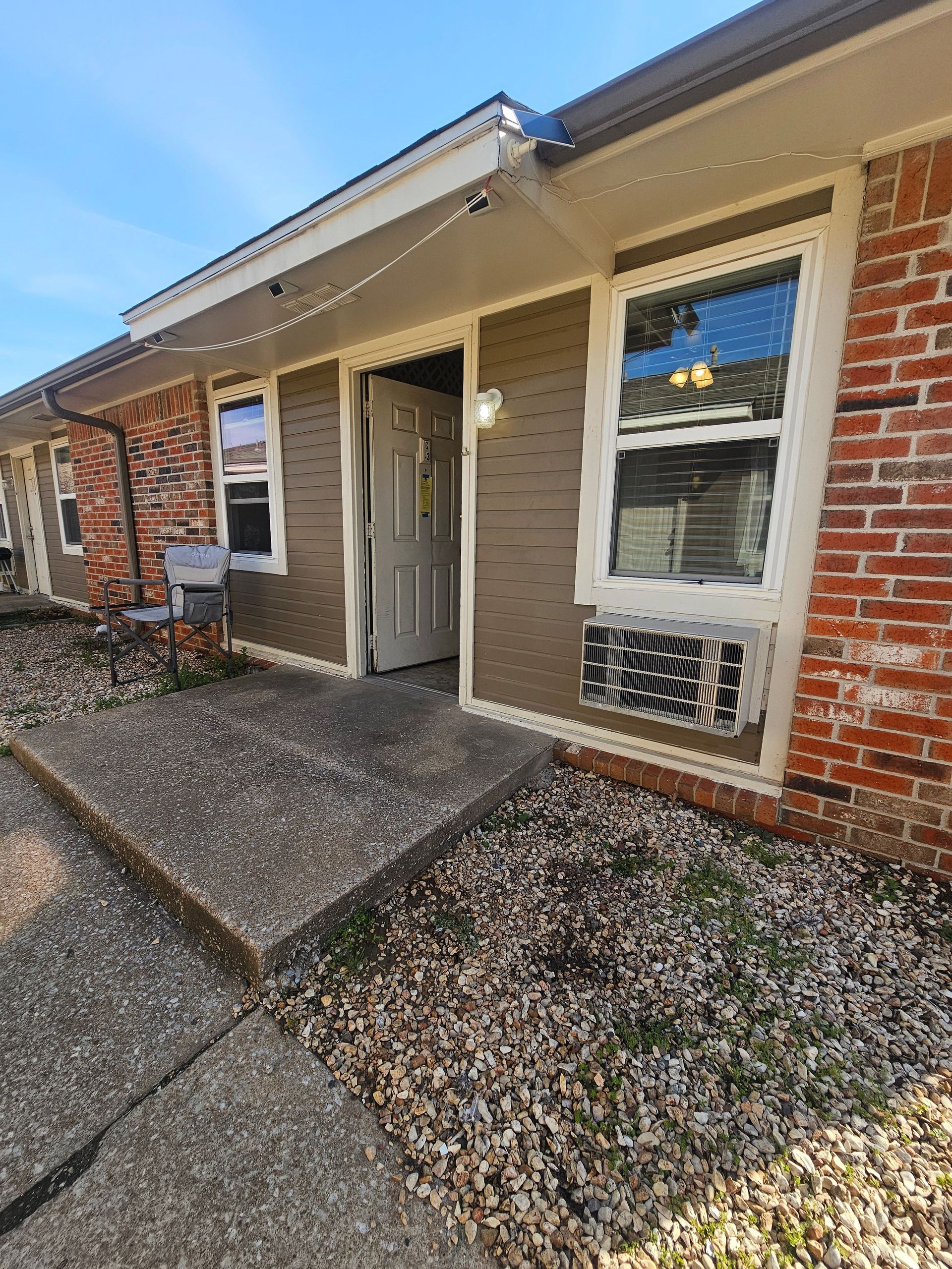 The front of a brick house with a concrete walkway leading to it.