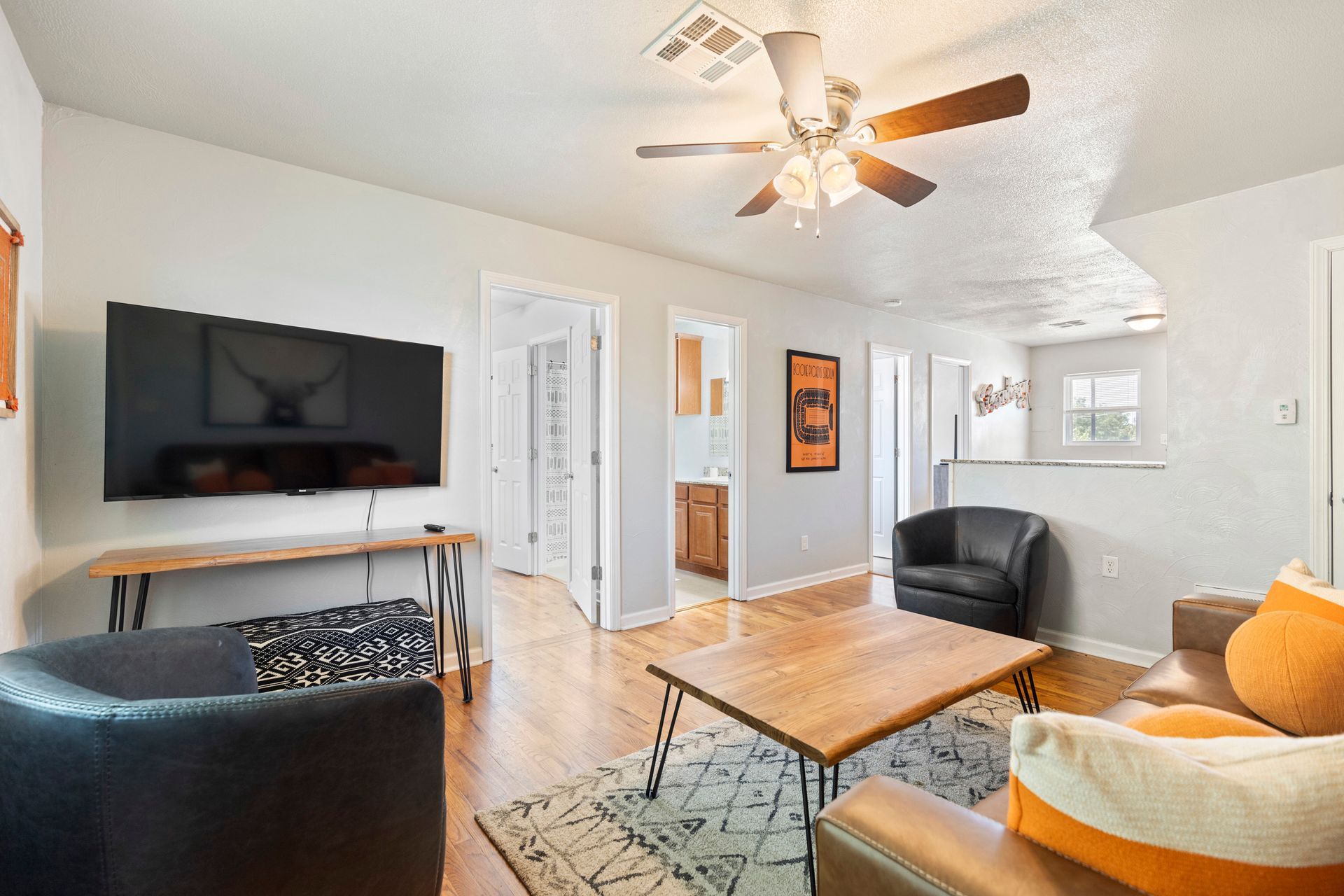 A living room with a ceiling fan and a flat screen tv.