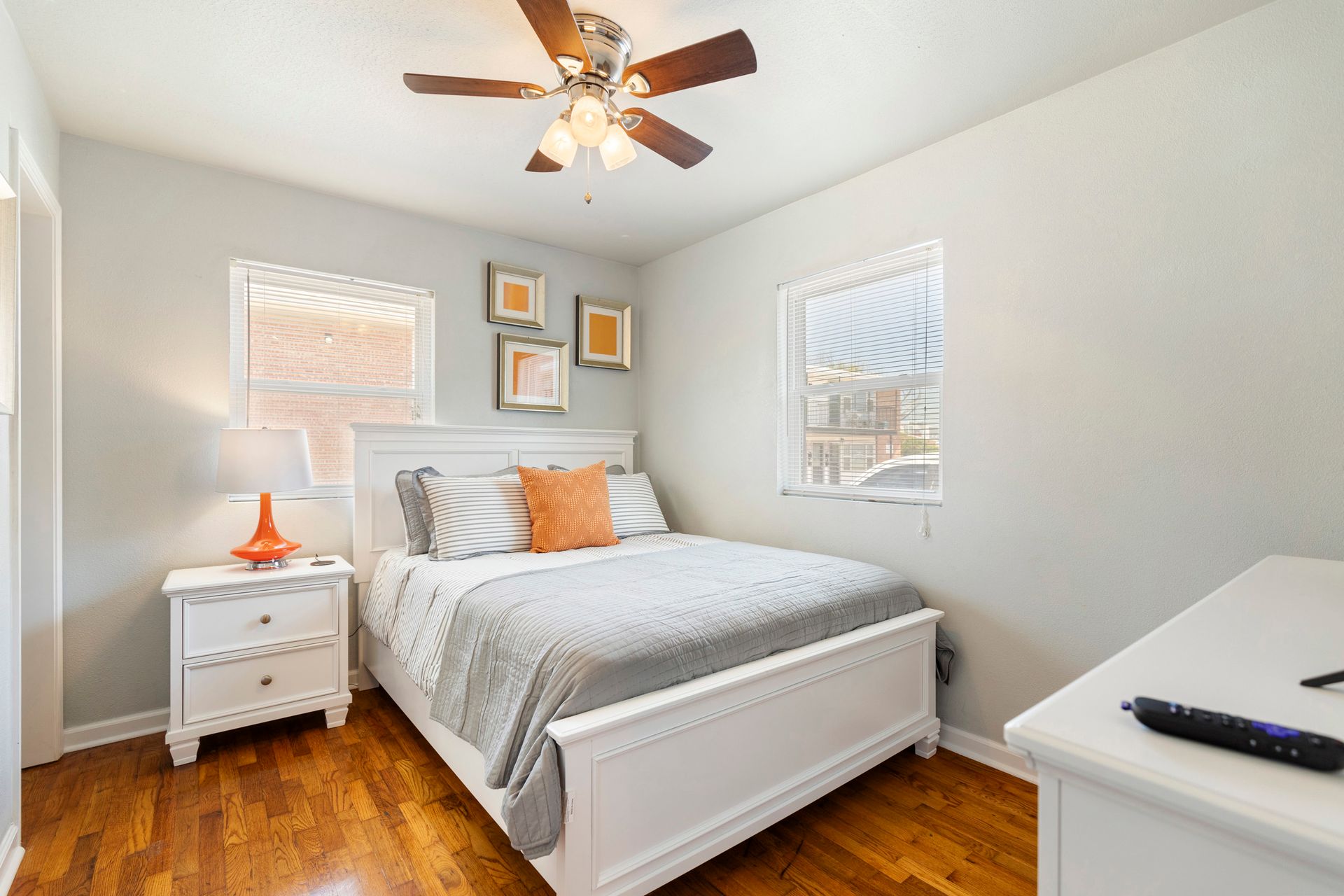 A bedroom with a bed , nightstand , dresser and ceiling fan.