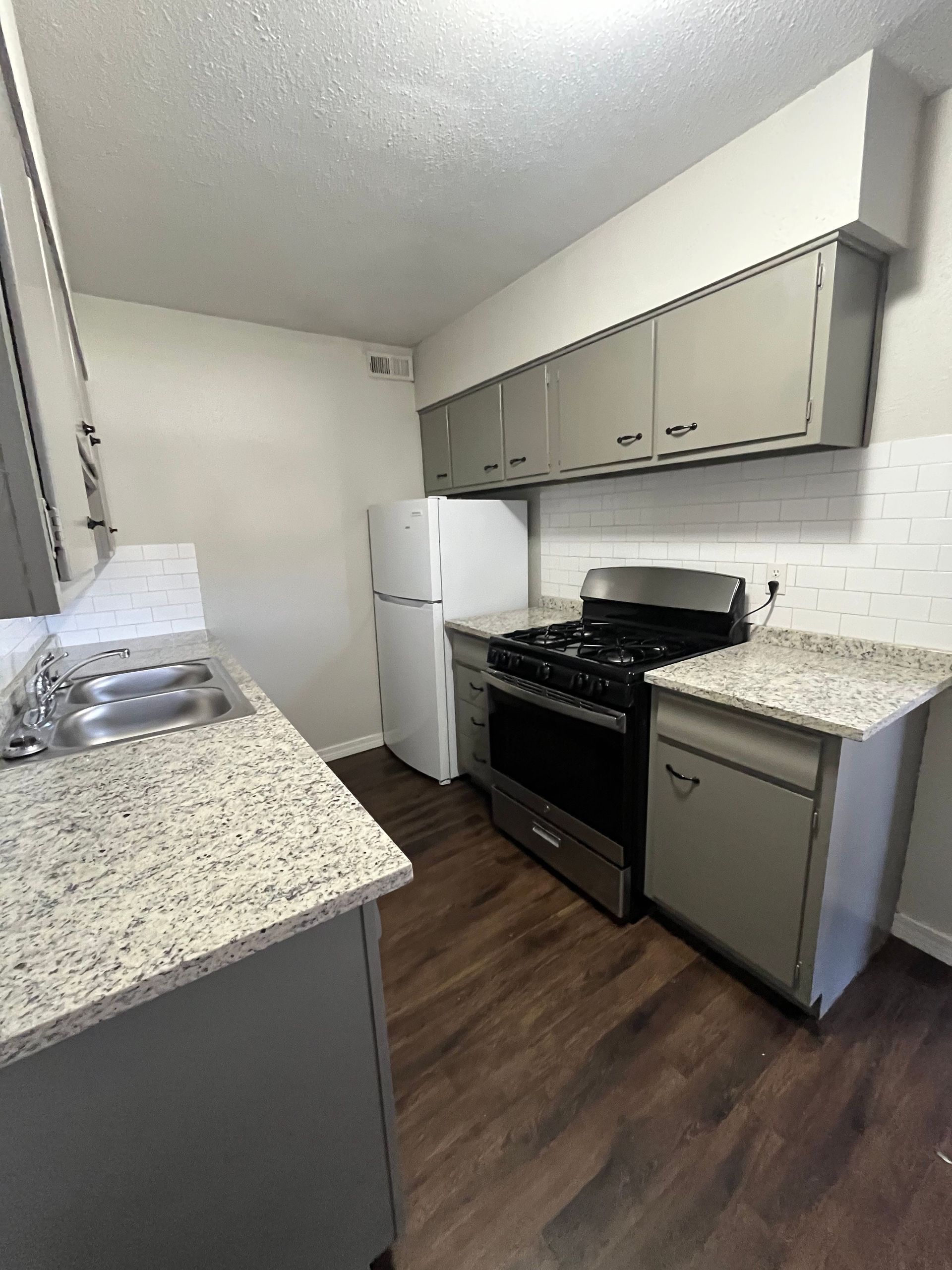 A kitchen with a stove , refrigerator , sink and dishwasher.