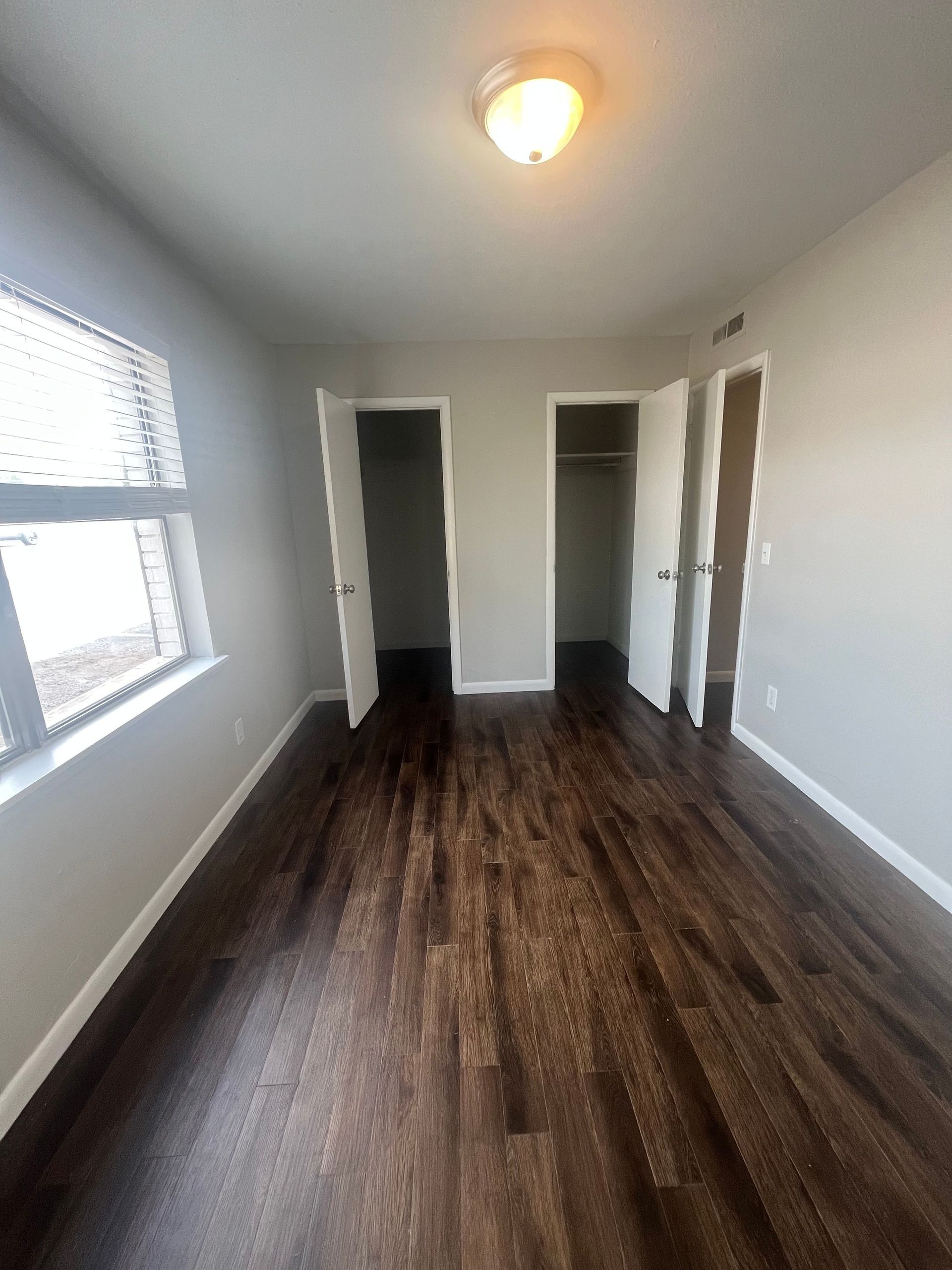 A bedroom with hardwood floors and two closets.