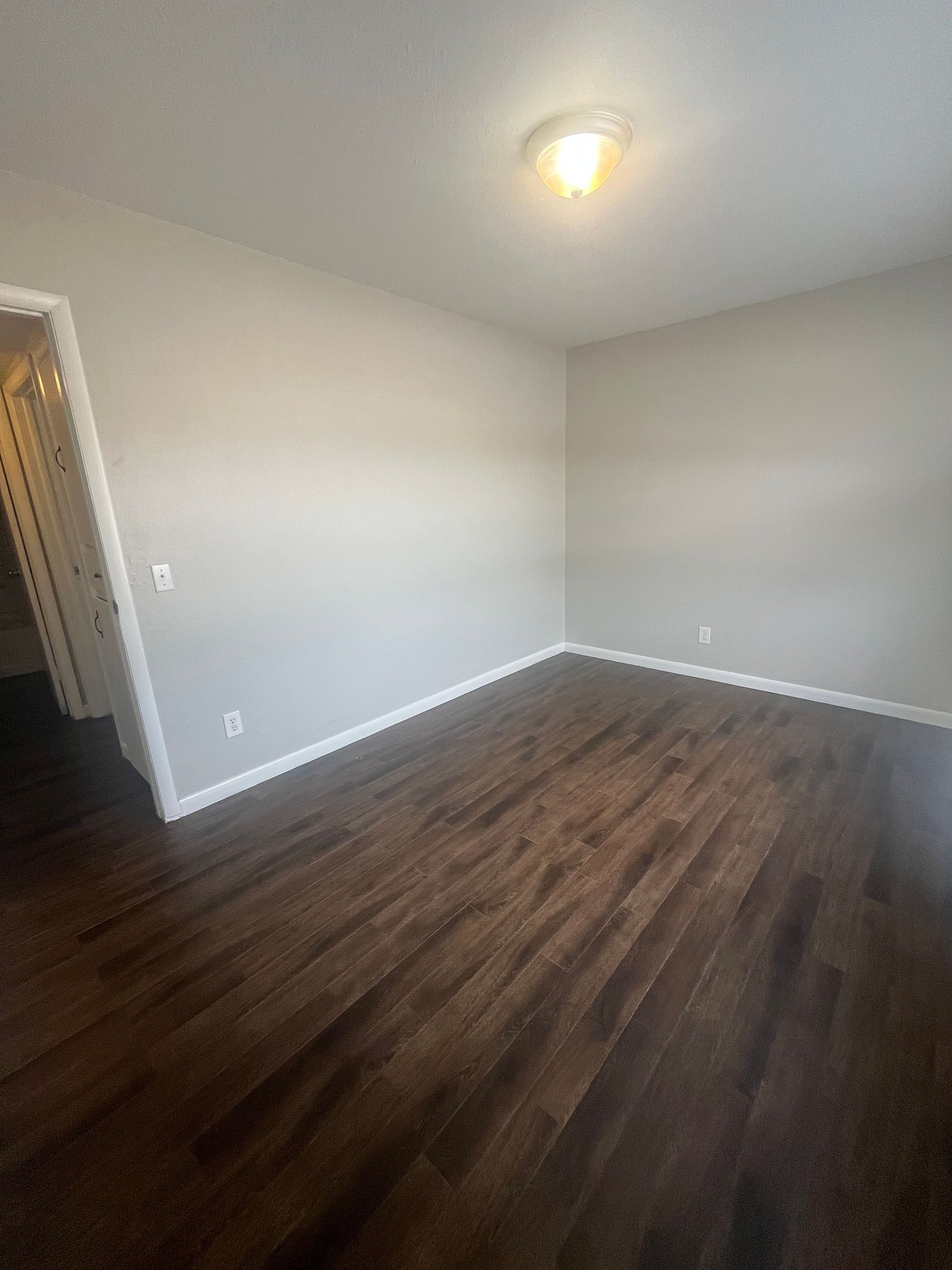 An empty living room with hardwood floors and white walls.