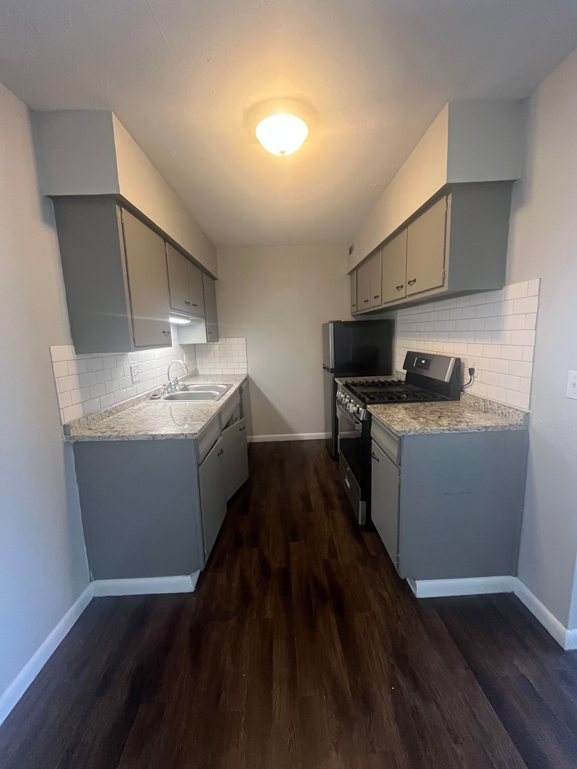 A kitchen with a stove , refrigerator , sink and cabinets.