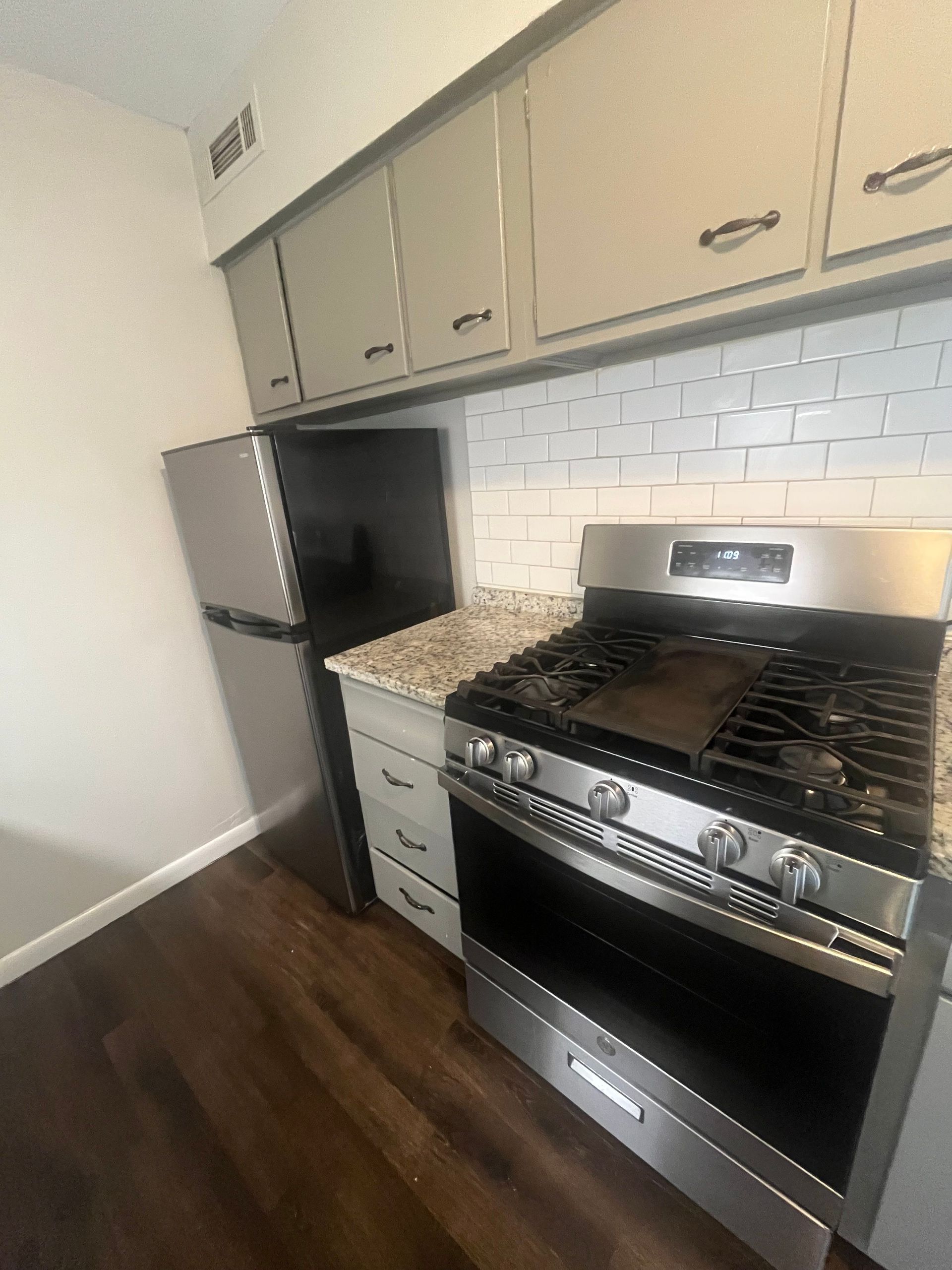 A kitchen with a stove , refrigerator , and cabinets.
