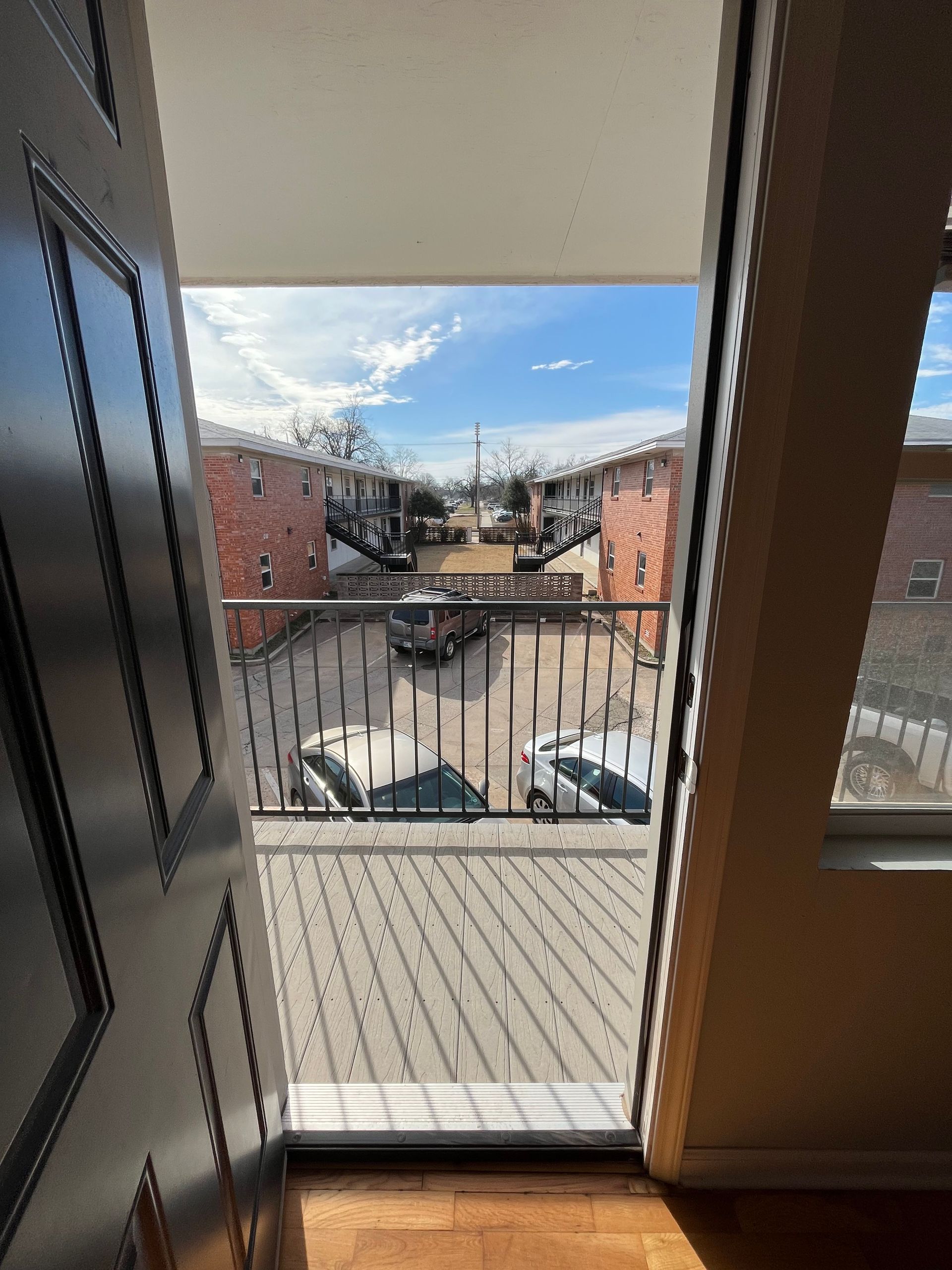 A balcony with a view of a city from a doorway.