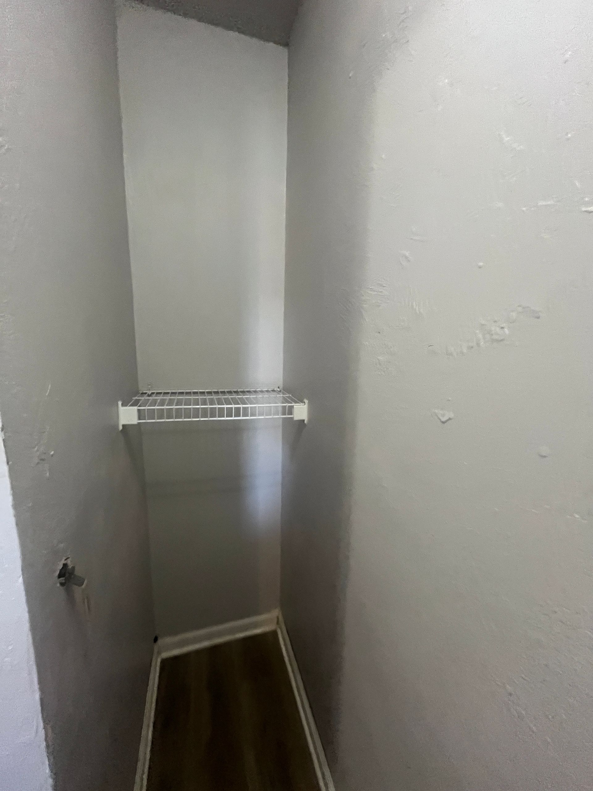 A closet with a clothes rack on the wall and a wooden floor.