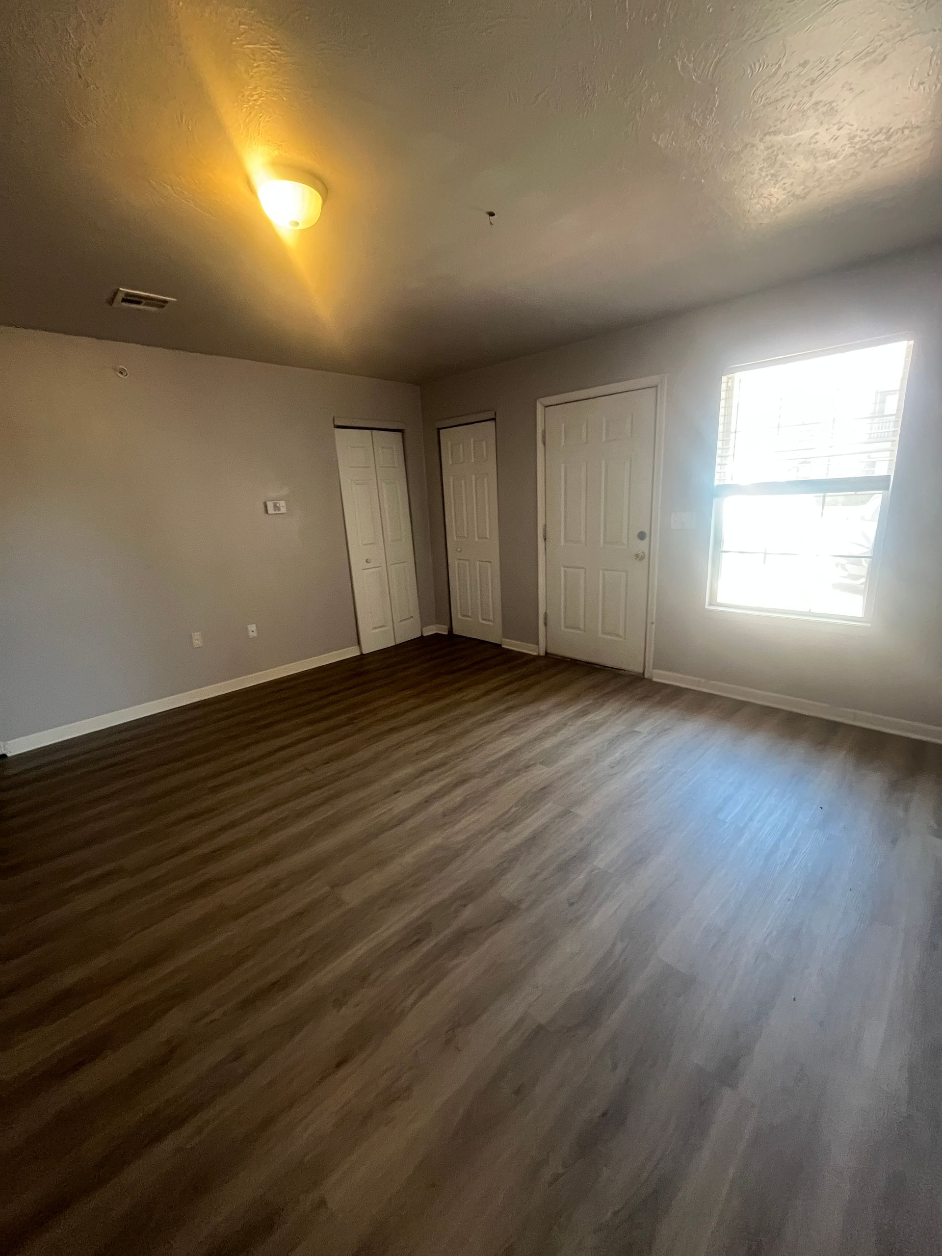 An empty living room with hardwood floors and a window.